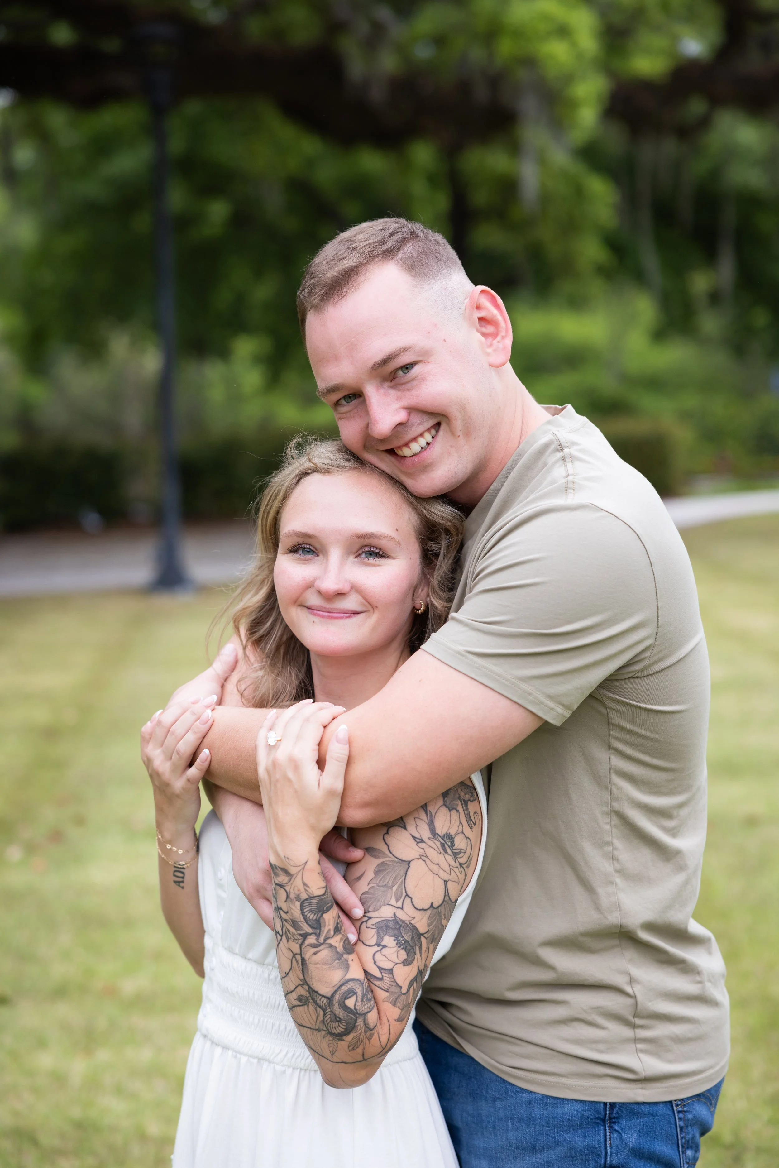 engaged couple hugging in green space