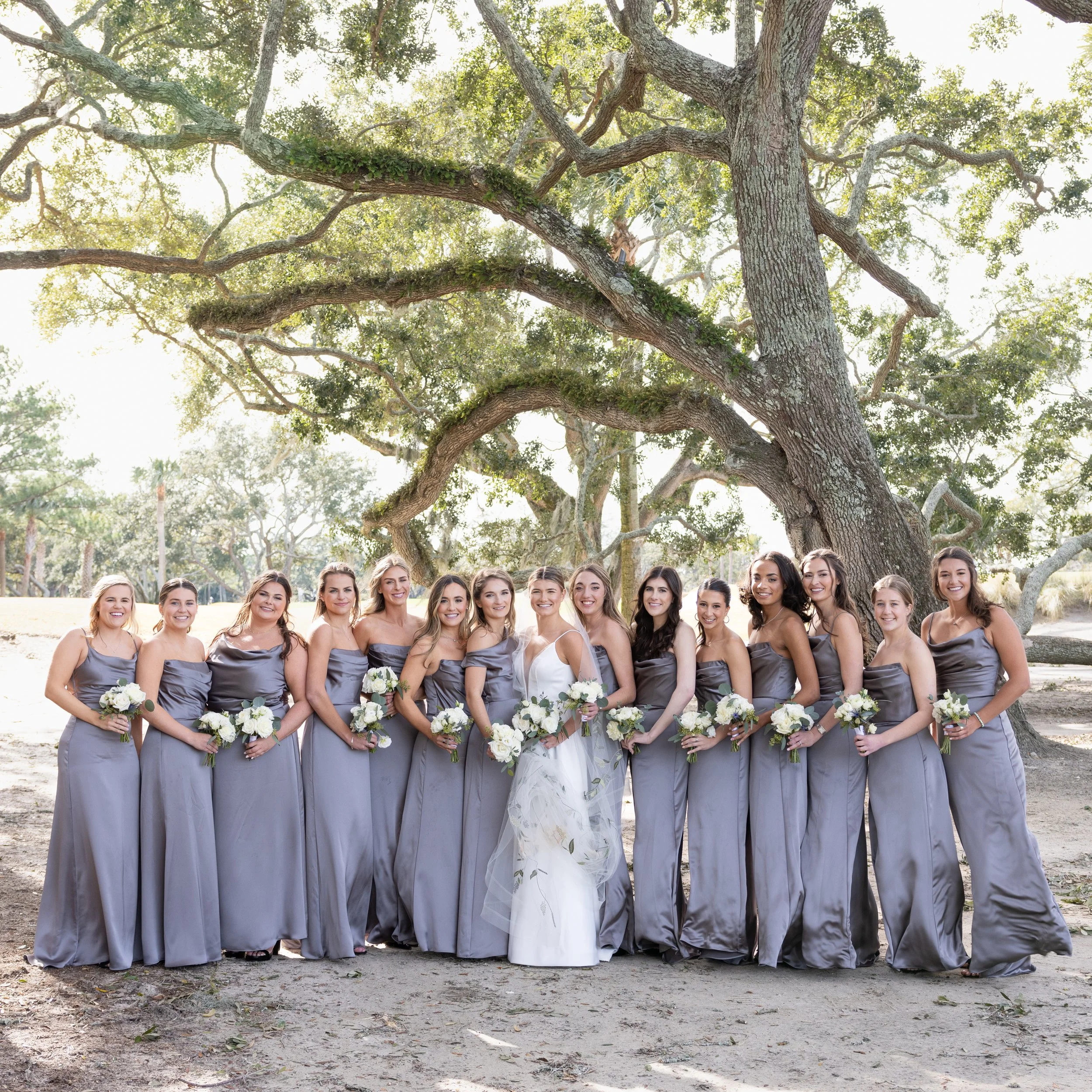 ladies bridal party posing under live oaks
