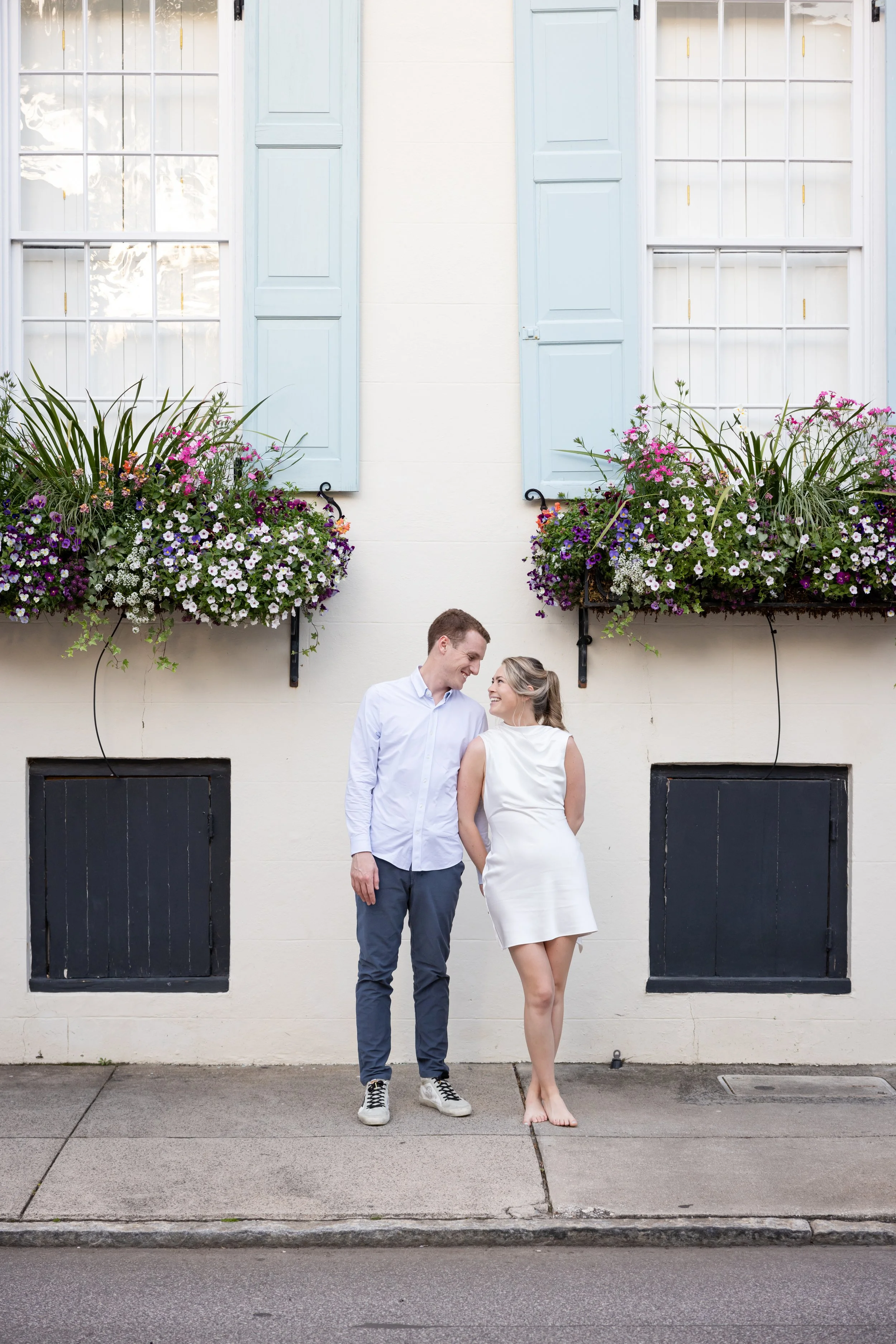 engaged flirty couple on street with window flower boxes