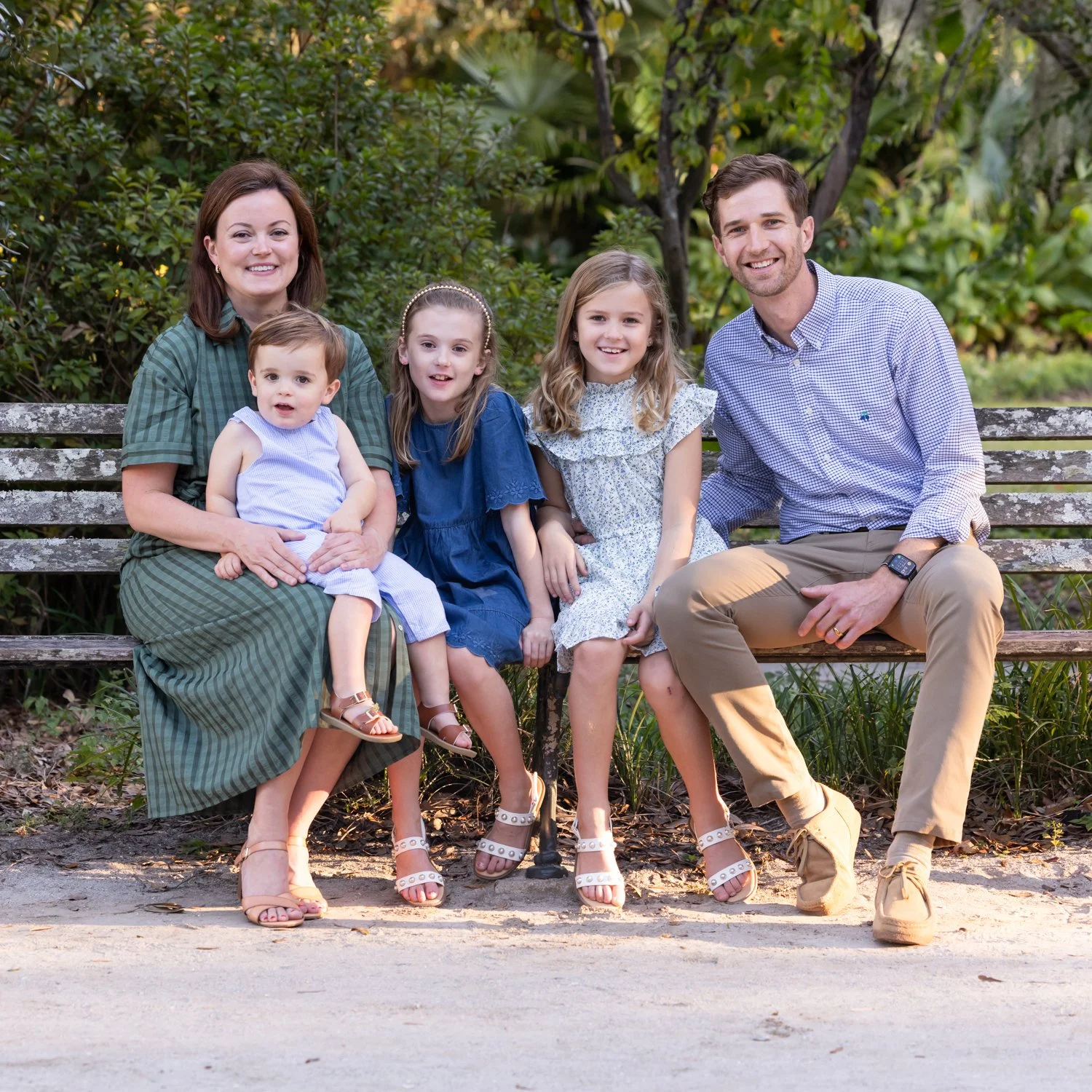 family of five sitting on the a park bench