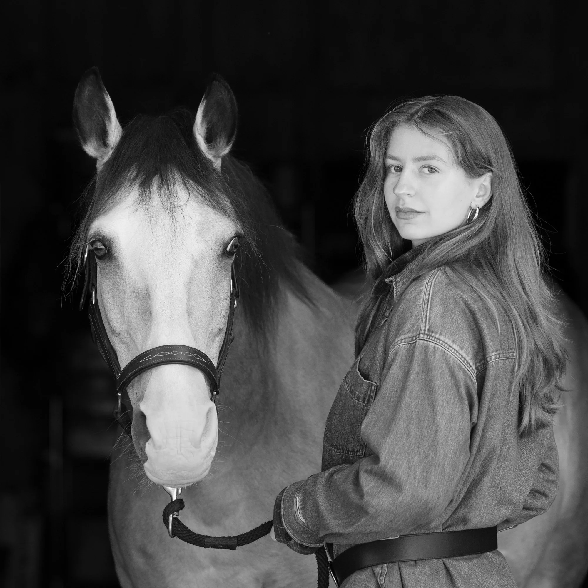 woman and buckskin horse on black background