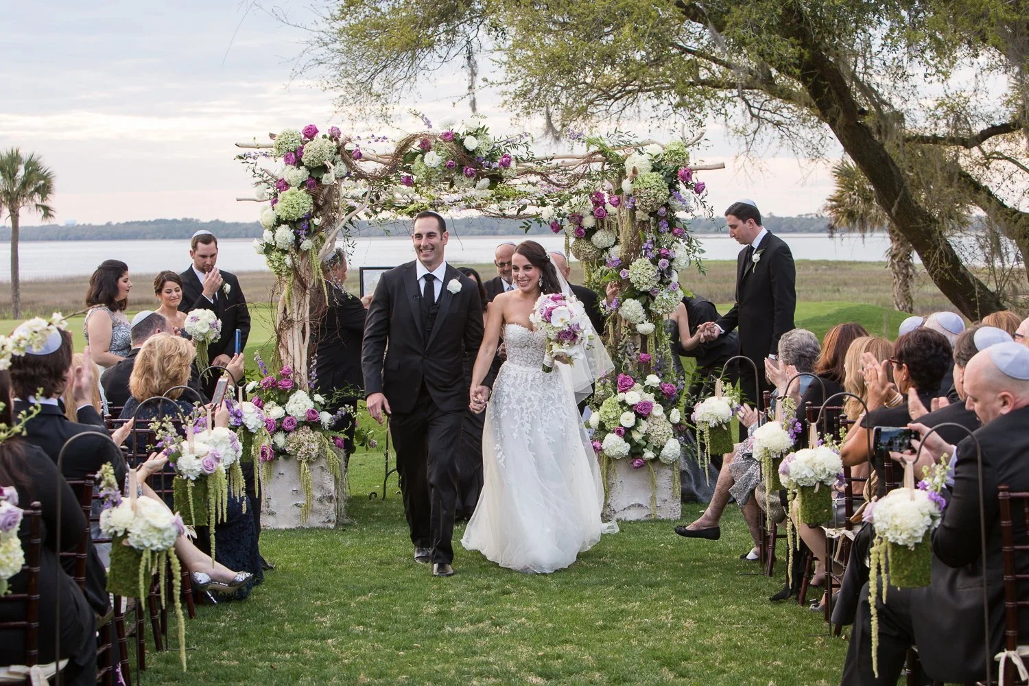 Just married bride and groom recessing down the aisle of outdoor ceremony