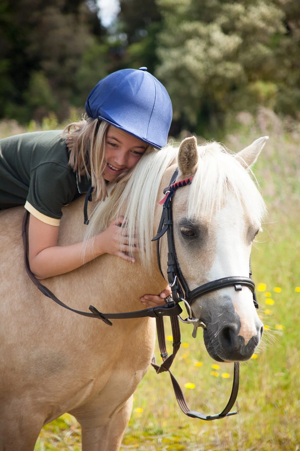 girl in blue helmet hugging Palomino
