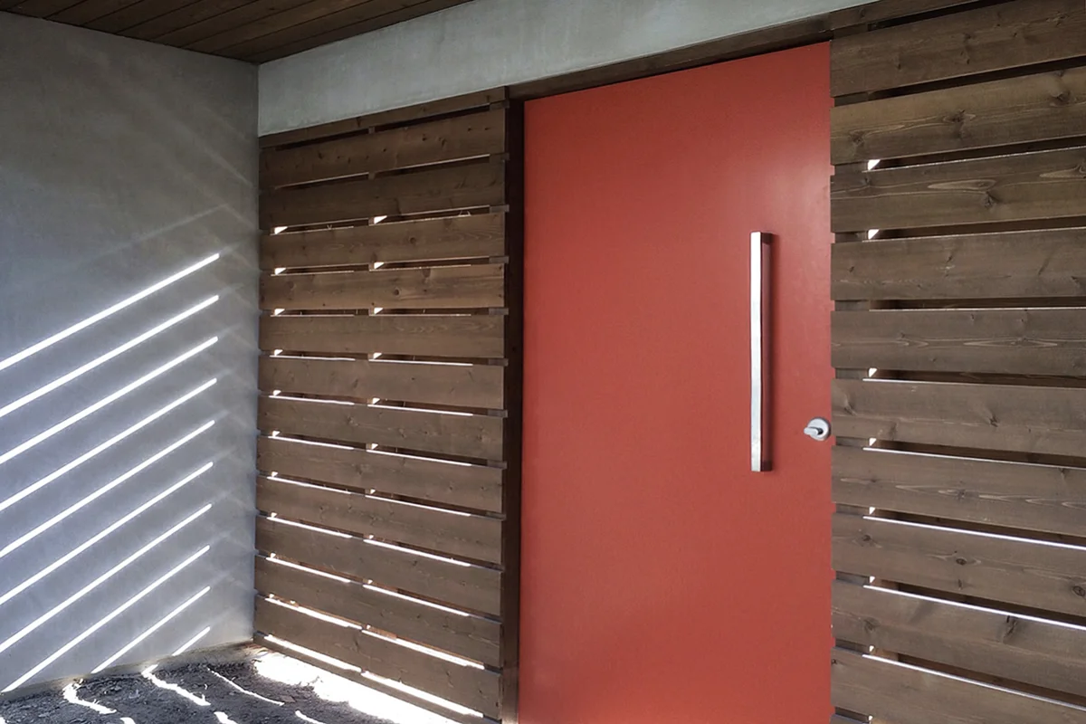 midcentury modern construction / orange pivot door at courtyard