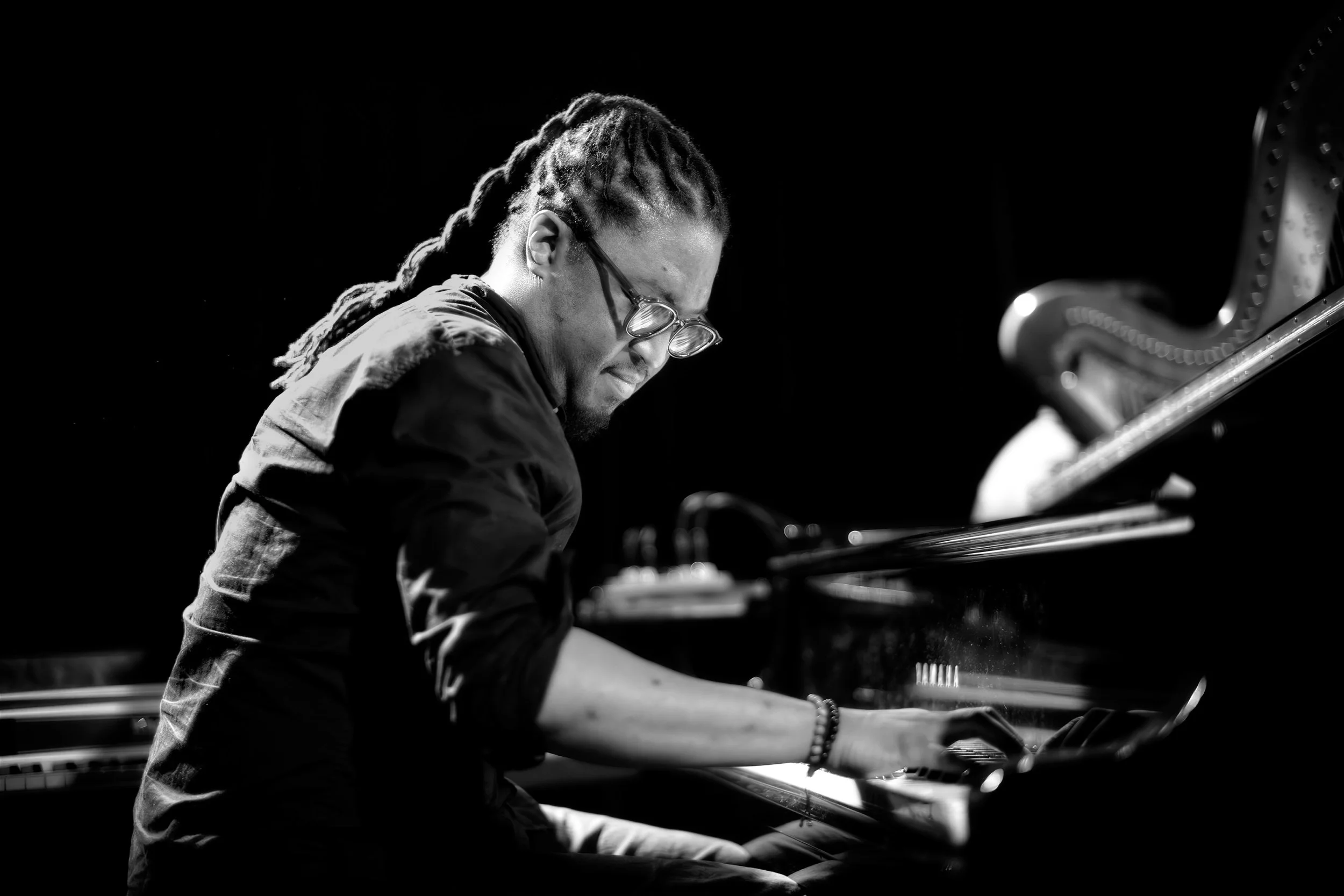 George Burton at the piano, hands on the keys, in stage light