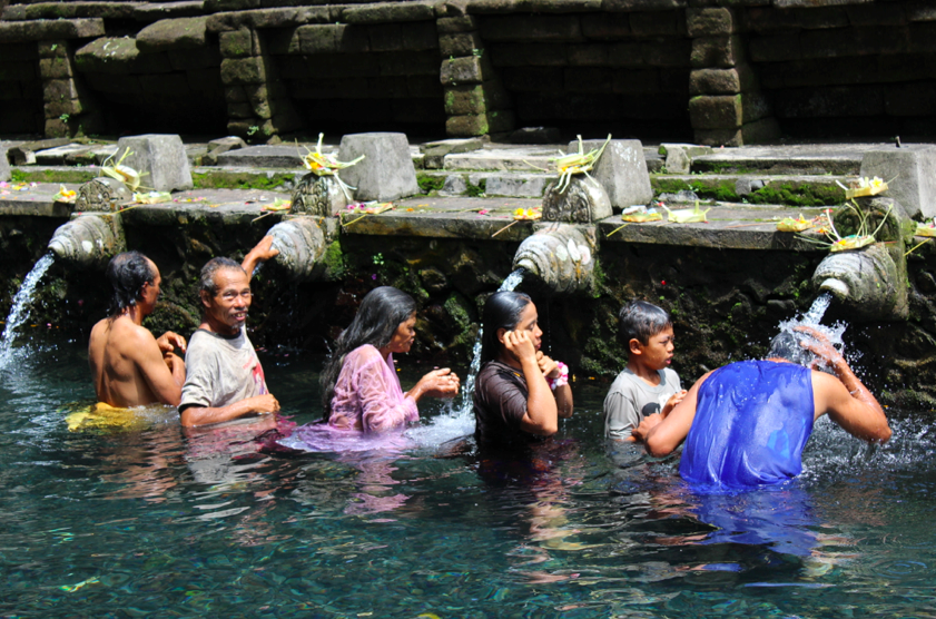 Balinese family moving through the line of water spouts