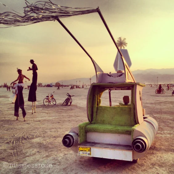 Stilt walkers at sunset and an art car