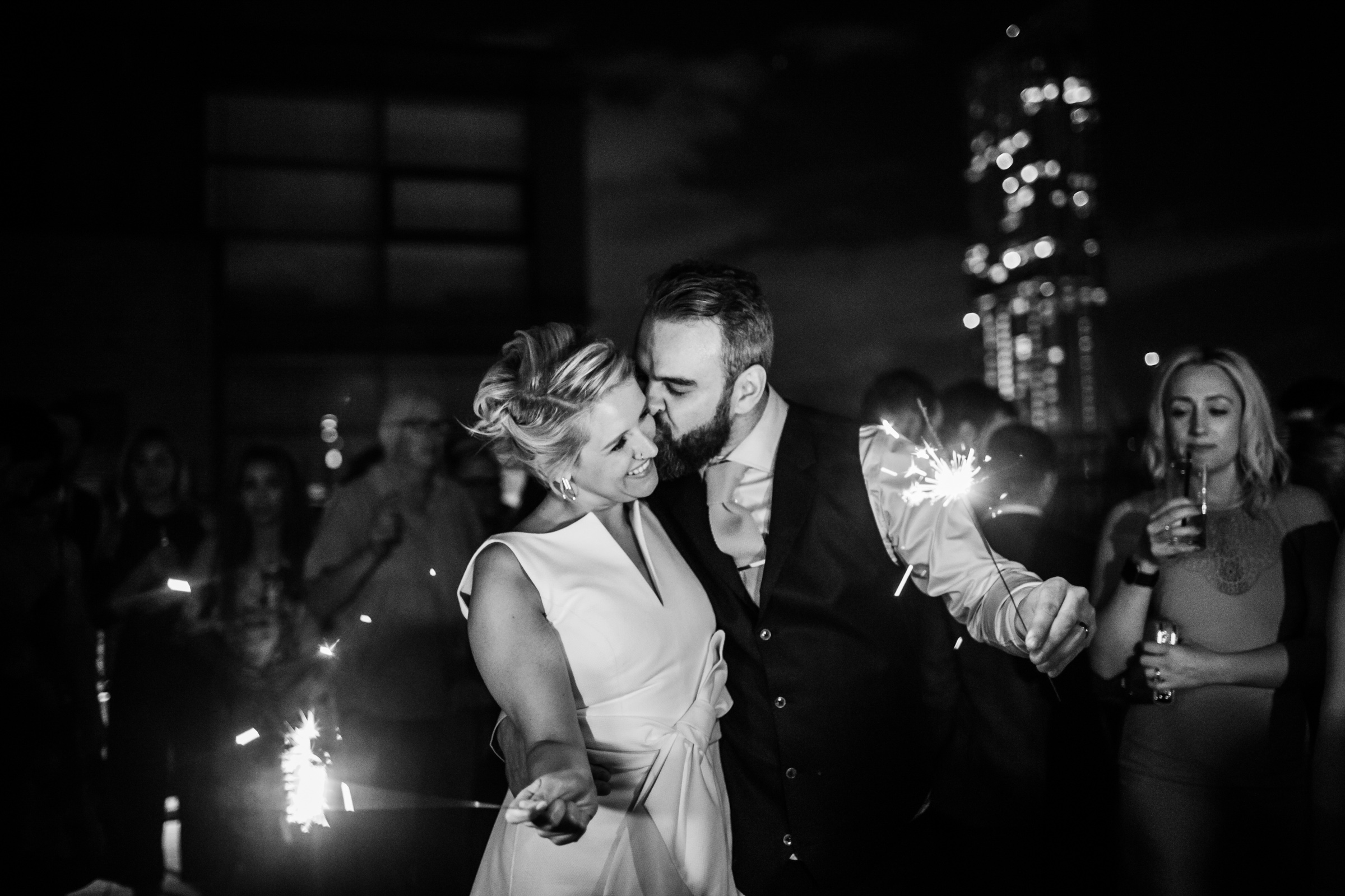 a bride and groom laugh with sparklers on the roof of great john street hotel manchester