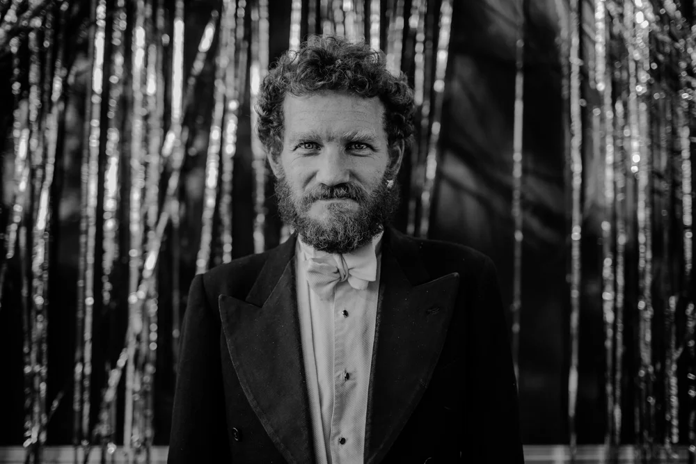 Dapper wedding guest in front of a sliver curtain at stanton hall and gardens