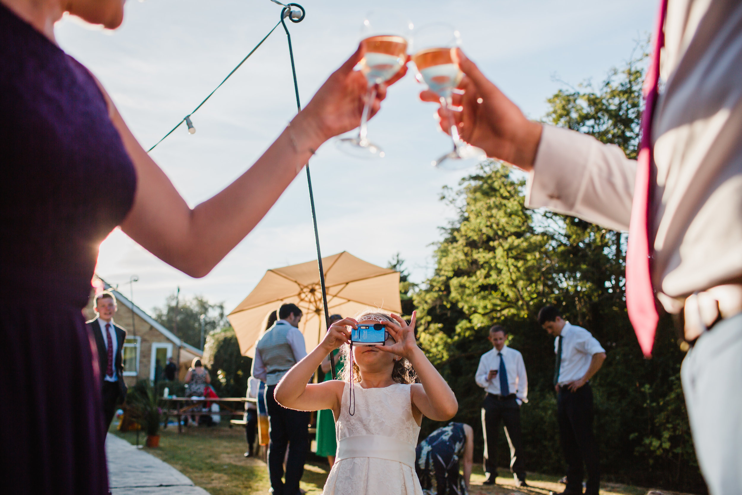 wedding guests toast with champagne while a child takes a picture