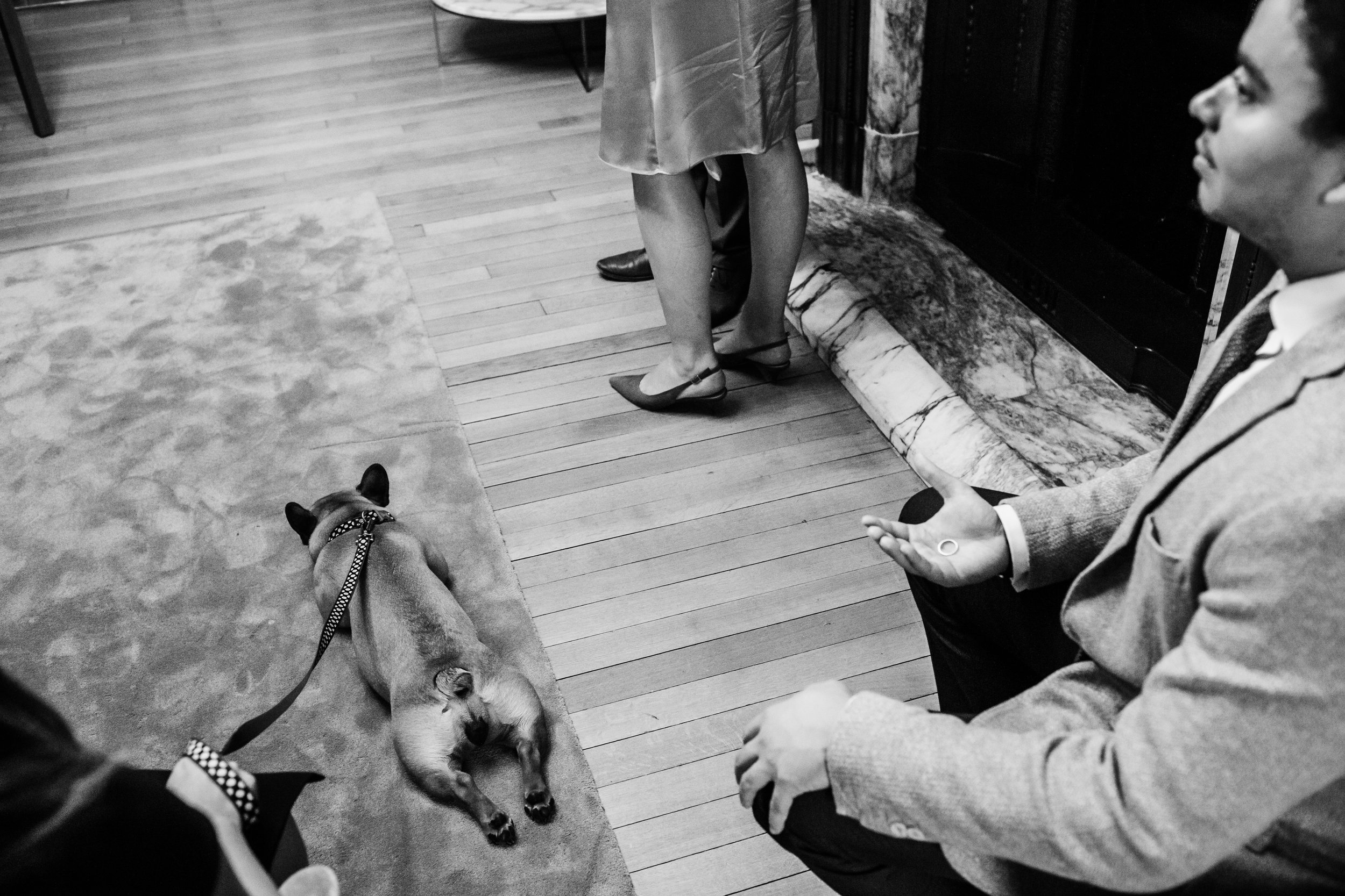 the feet of the bride and groom can be seen while the best man holds the rings and a french bulldog lays on the fllor asleep