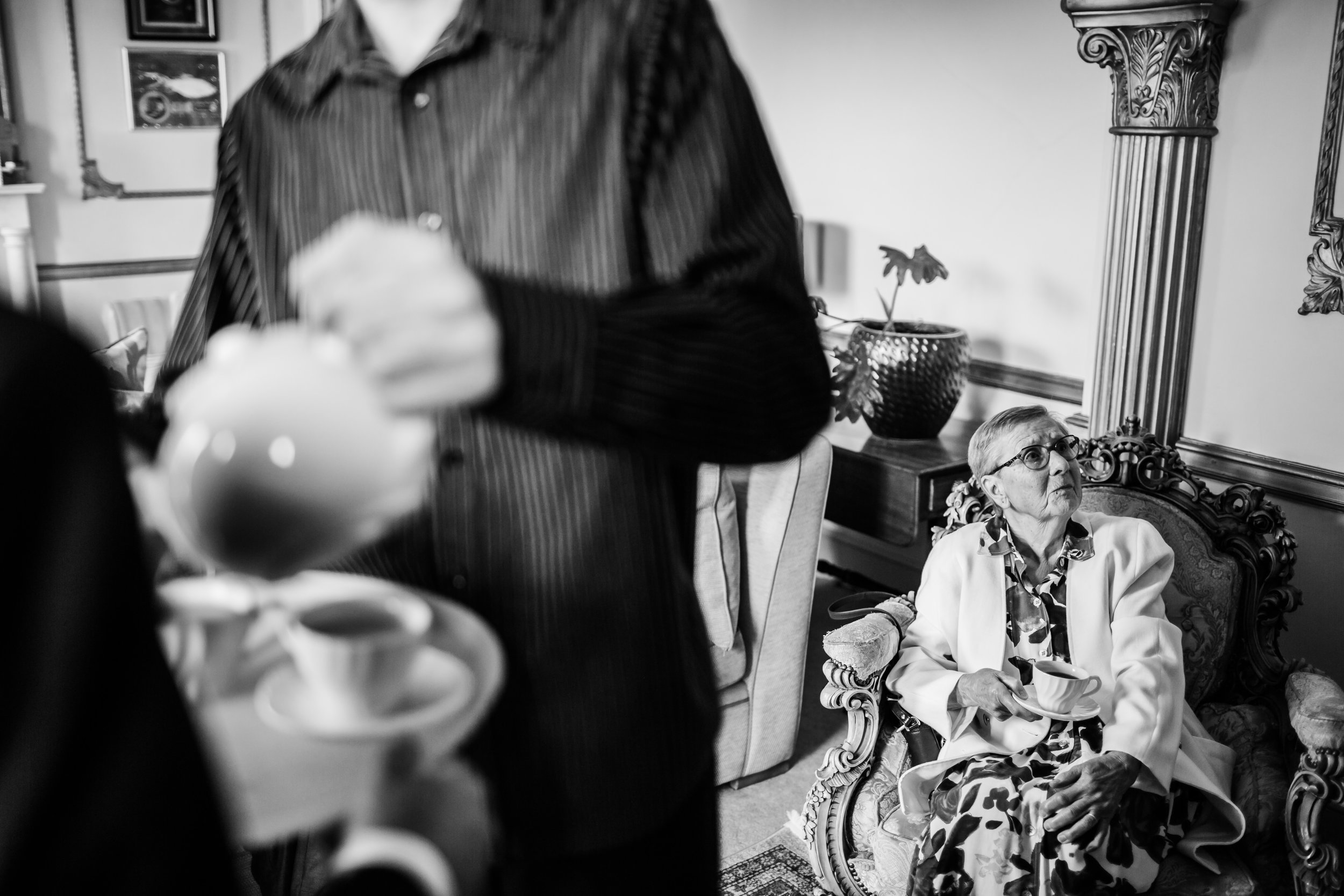 a man pours tea while gran drinks her tea behind him at a wedding