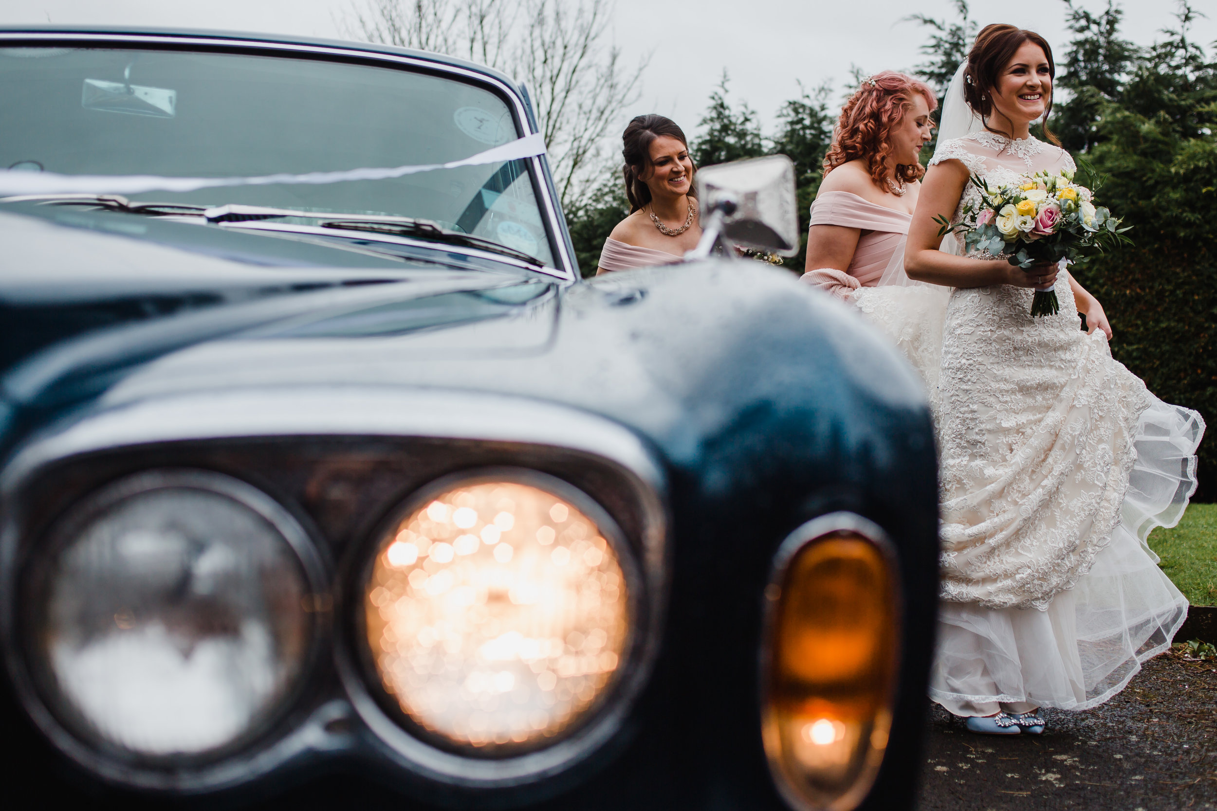 a bride and her bridesmaids arrive at a wedding in a rolls royce