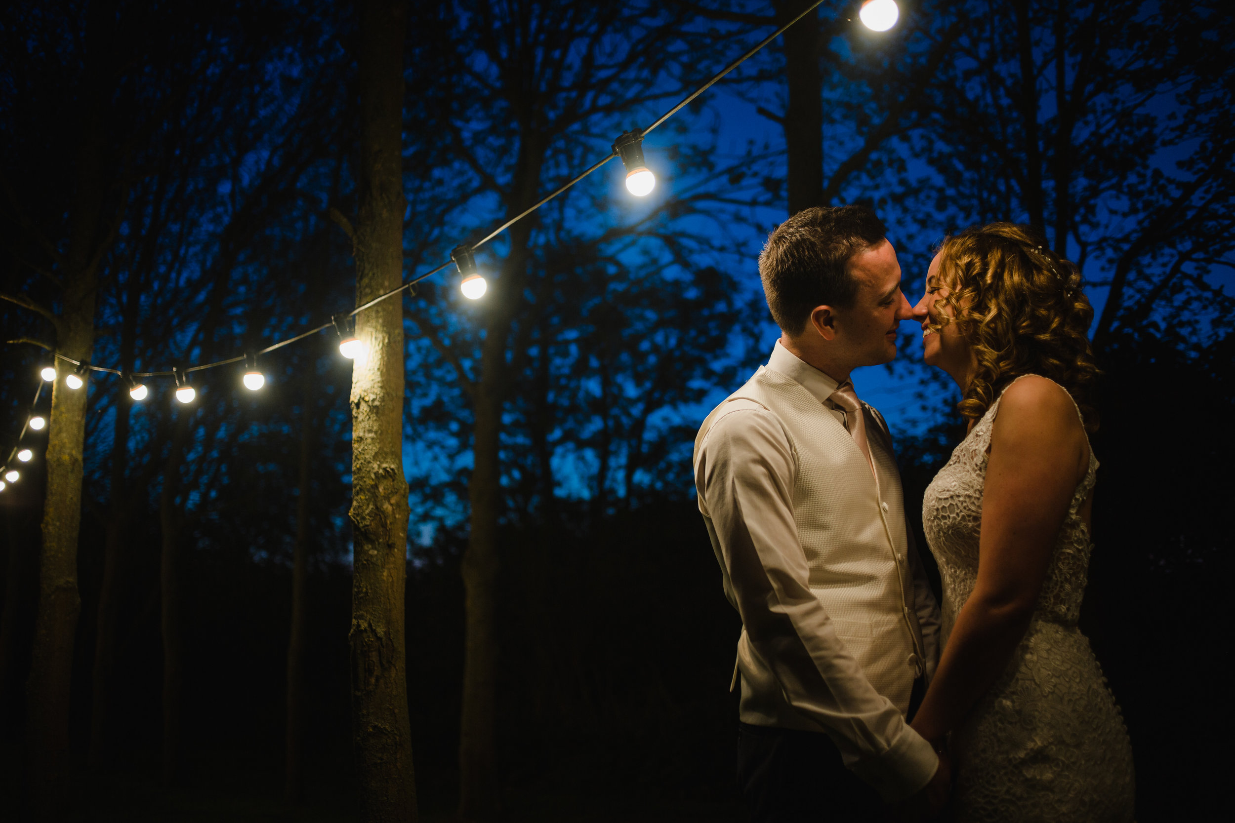 a bride and groom kiss under festoons at shushtoke barn