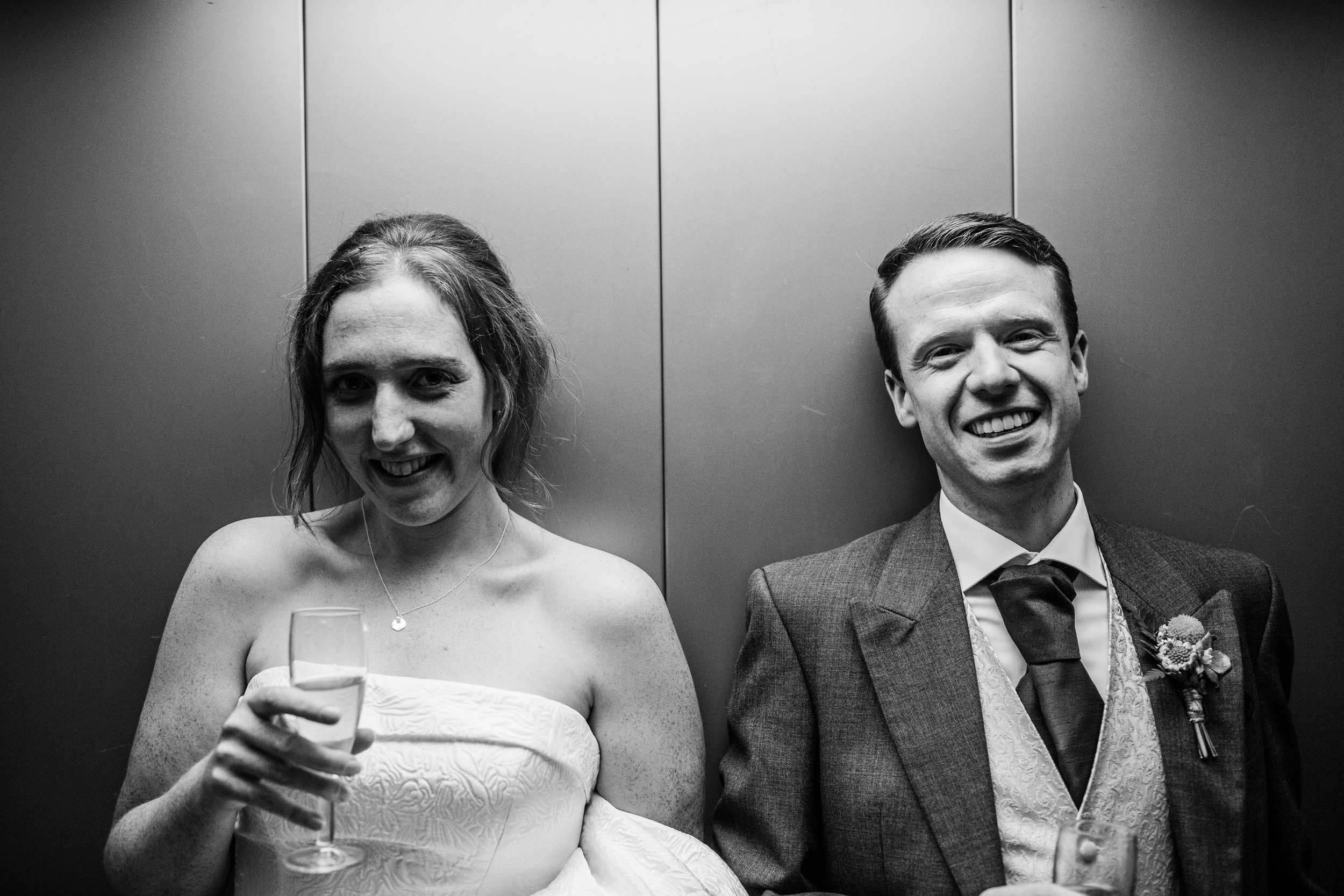a bride and groom laugh in a lift at quarry bank