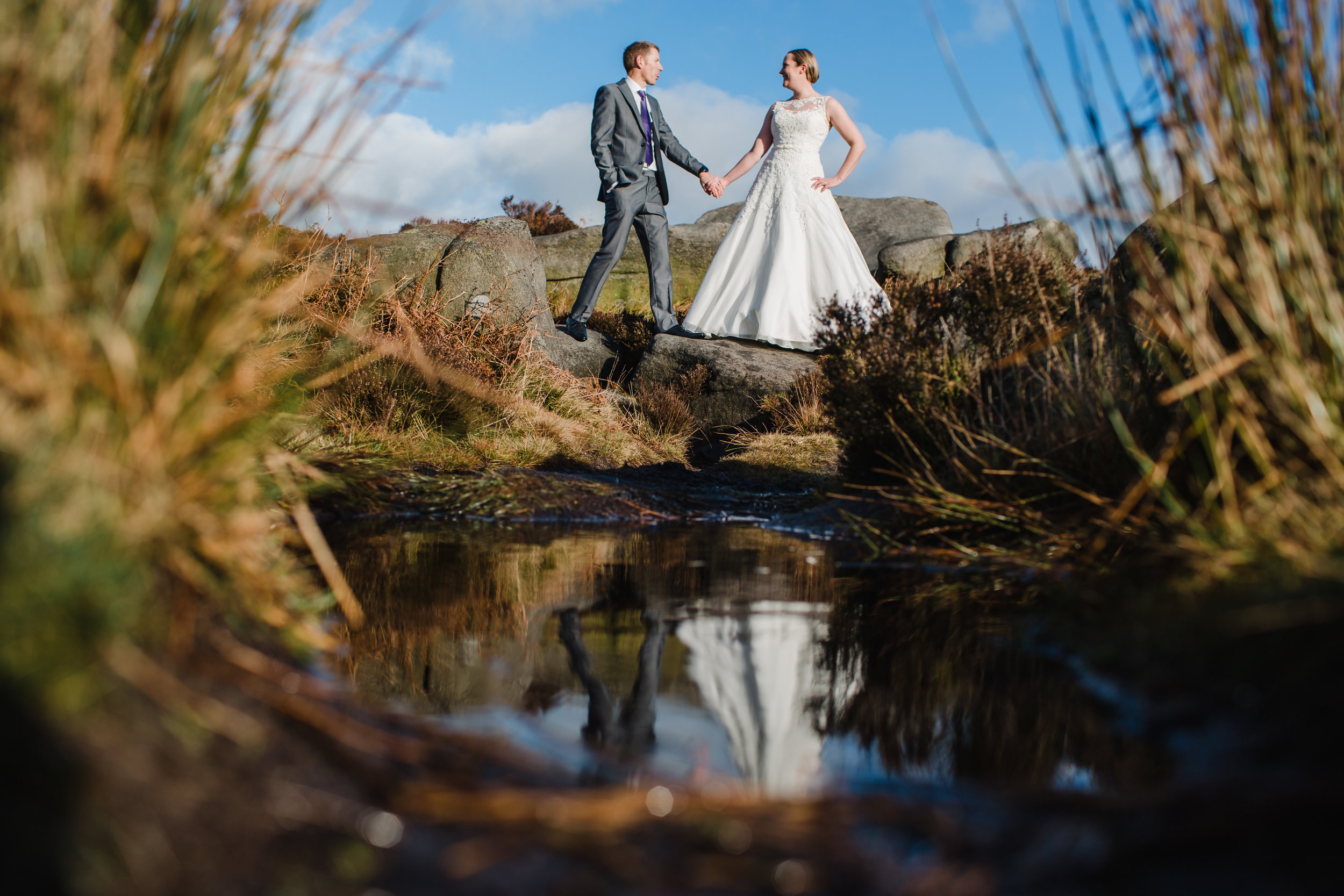 a bride and groom reflected in a puddle