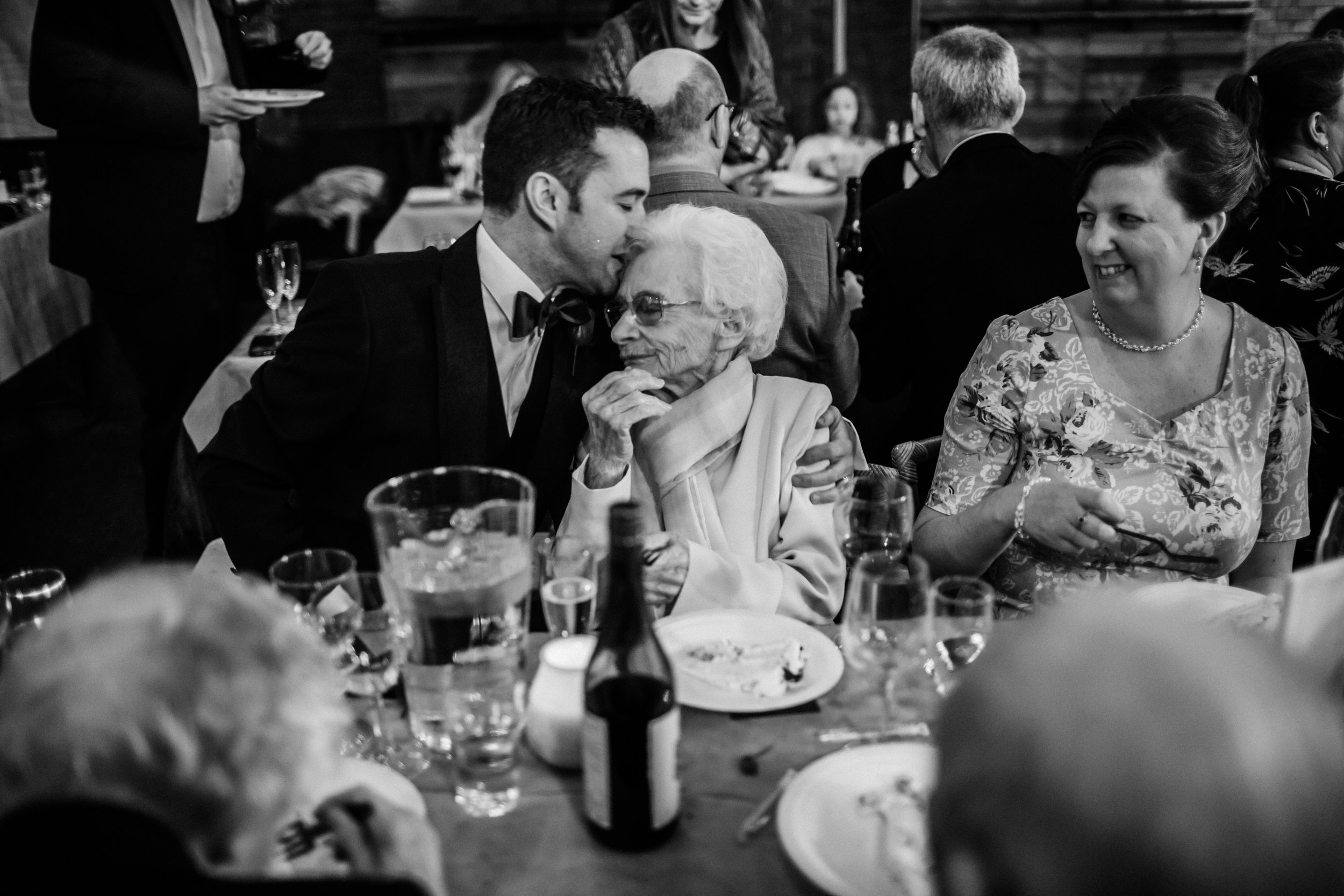 a groom kisses his grandma at a wedding