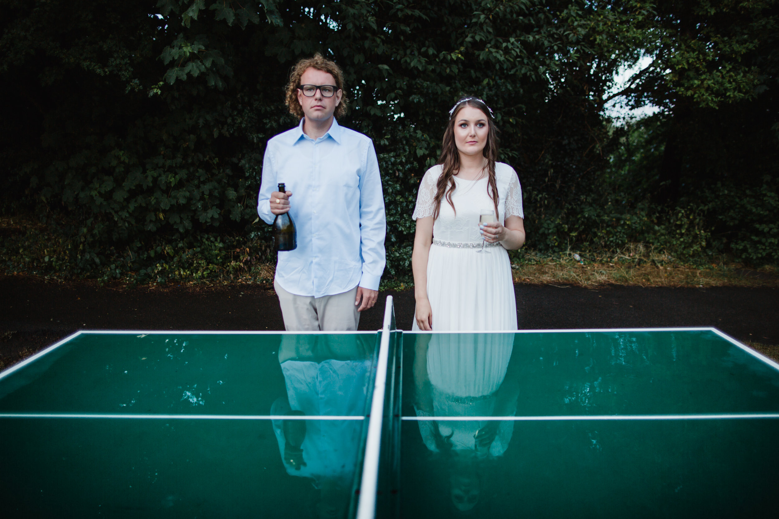 a bride and groom pose in front of a table tennis table