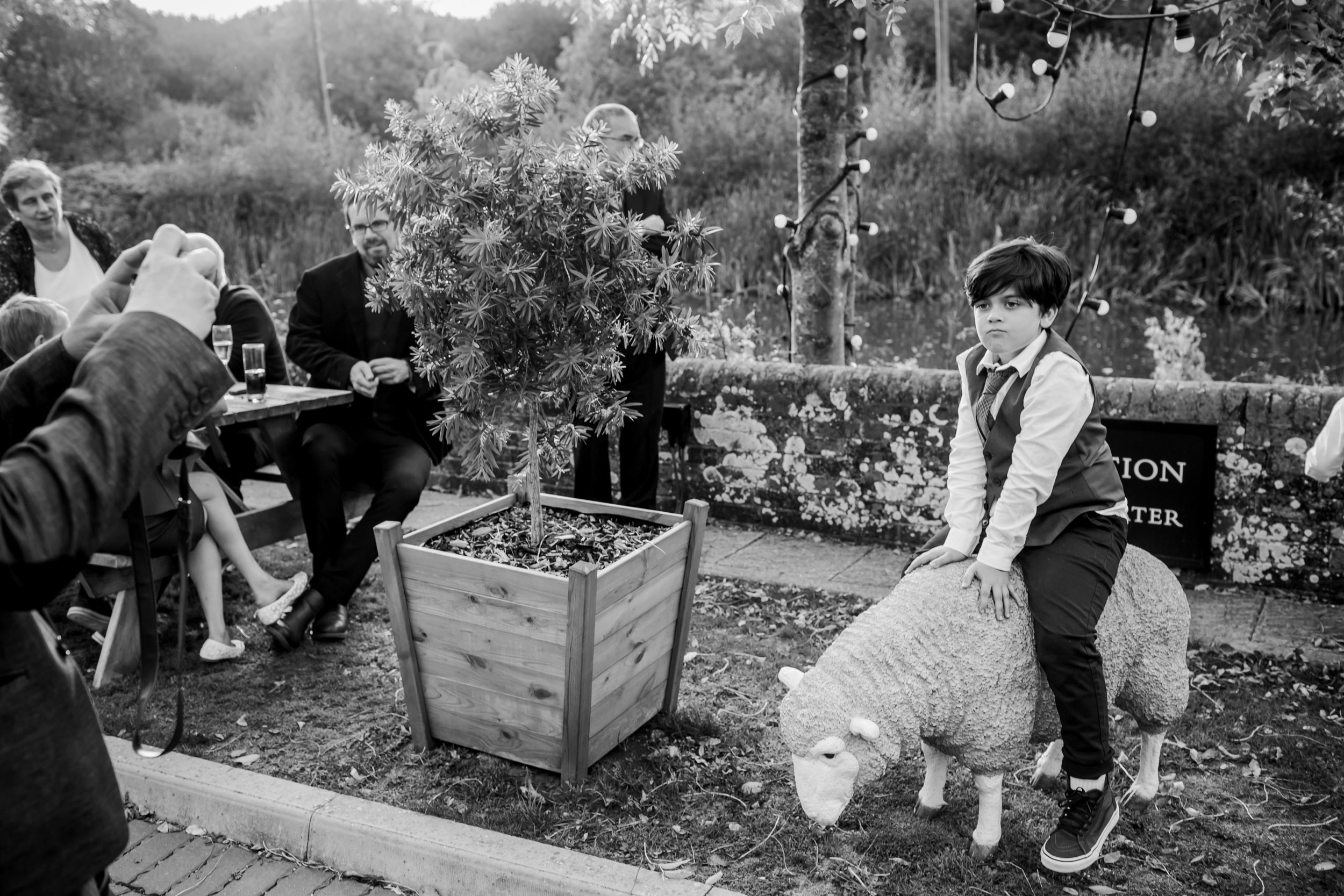 a child poses on a plastic sheep while someone takes a photo