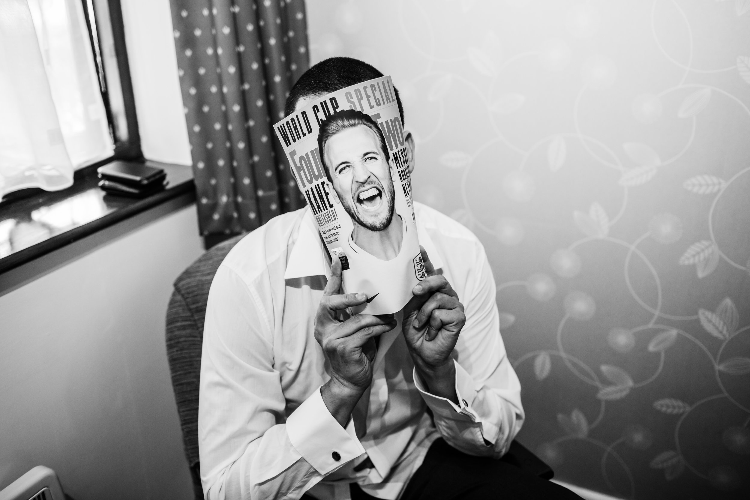 a groomsman hiding behind a magazine before a wedding