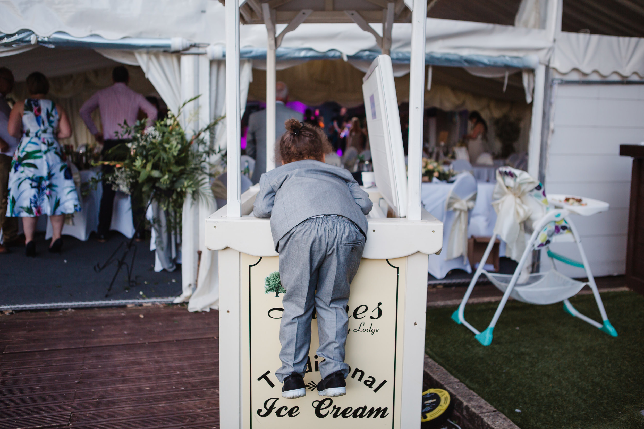  a child climbs into an ice cream freezer at a wedding