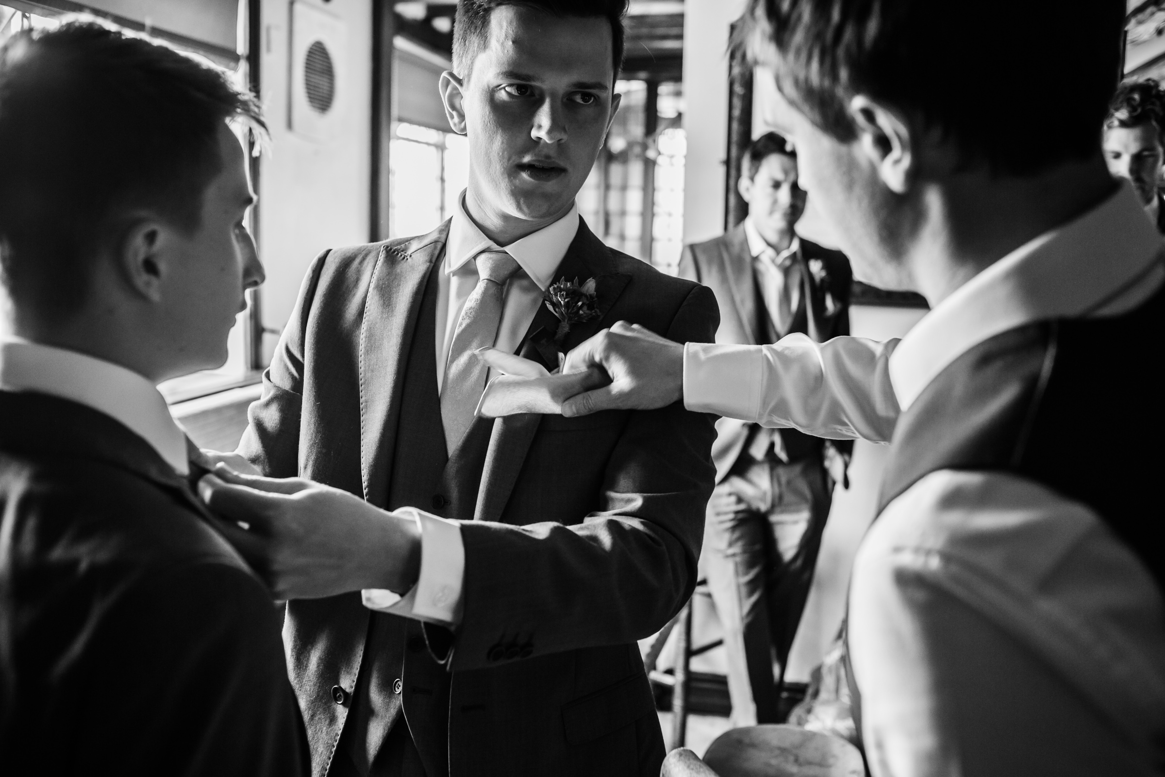 The groom has his flower attached before his wedding.