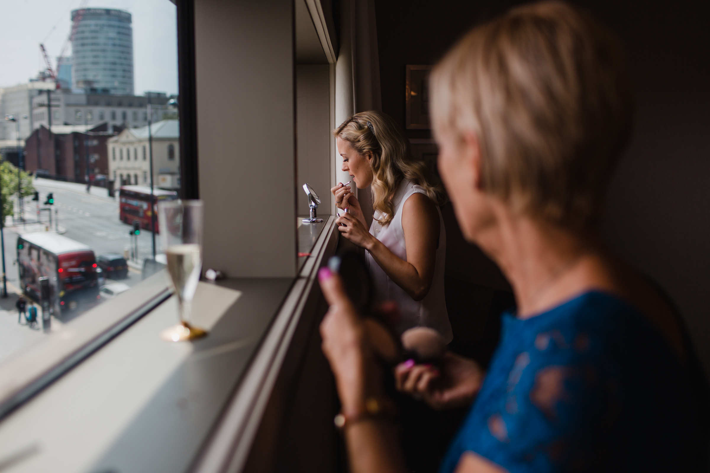 a bride puts het make up on while her mother watches before her Birmingham wedding. 