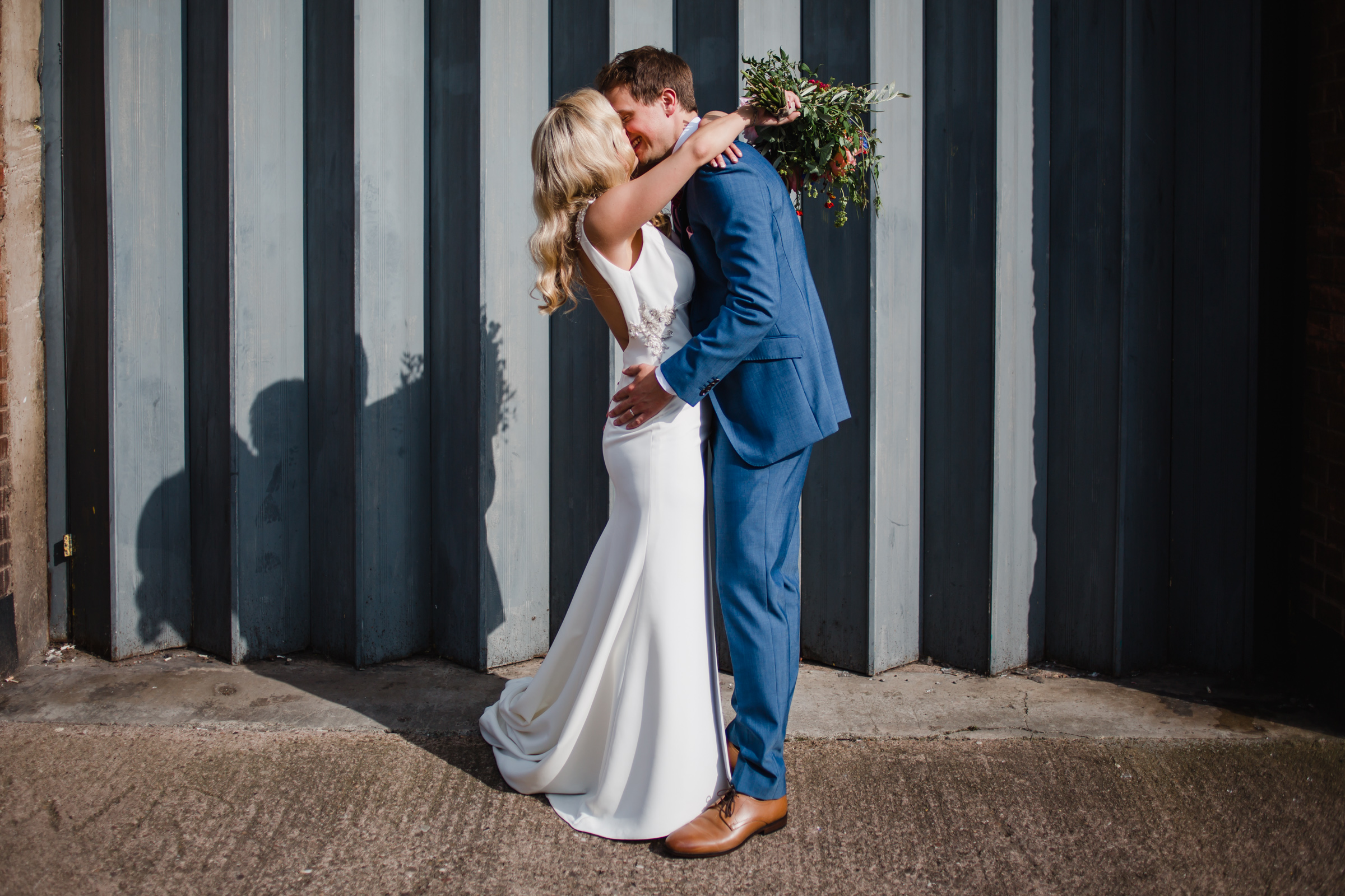 a bride and groom kiss in front of an industrial shutter door in digbeth Birmingham