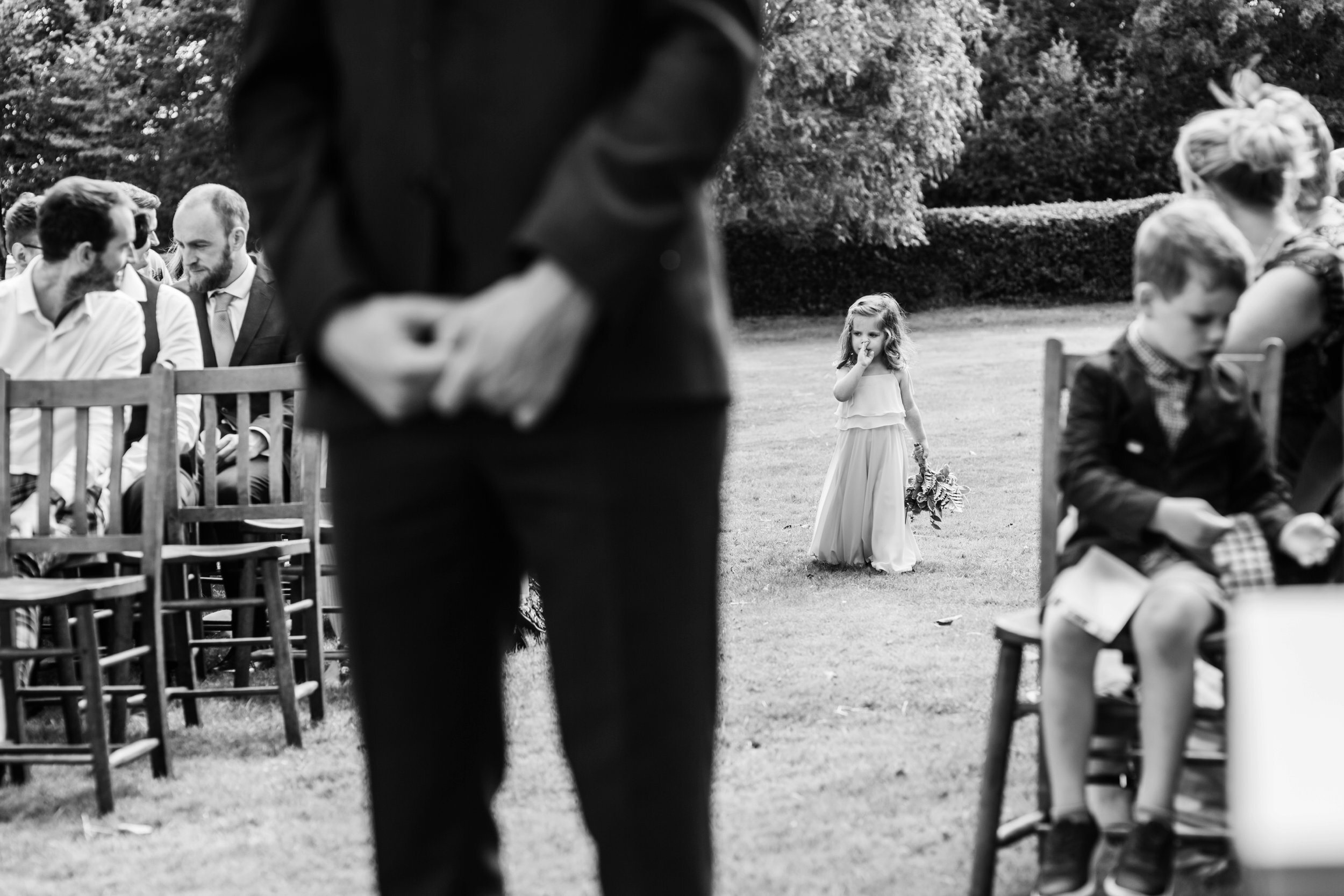 A groom watches a flower girl working down an aisle