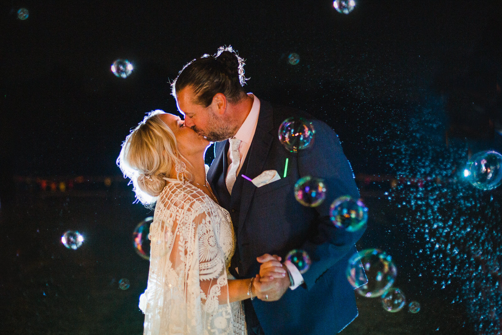 a bride and groom kiss surrounded by bubbles