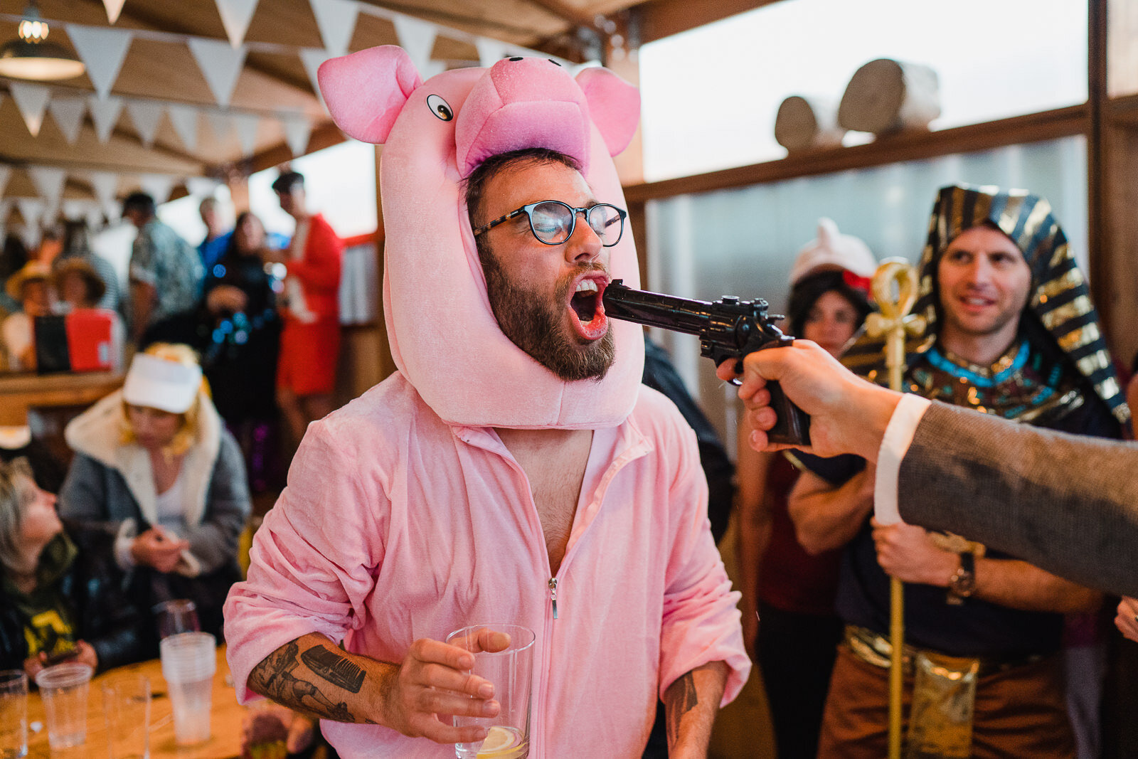 a groom dressed as a pig has a shot of tequila form a handgun at Fforest in wales