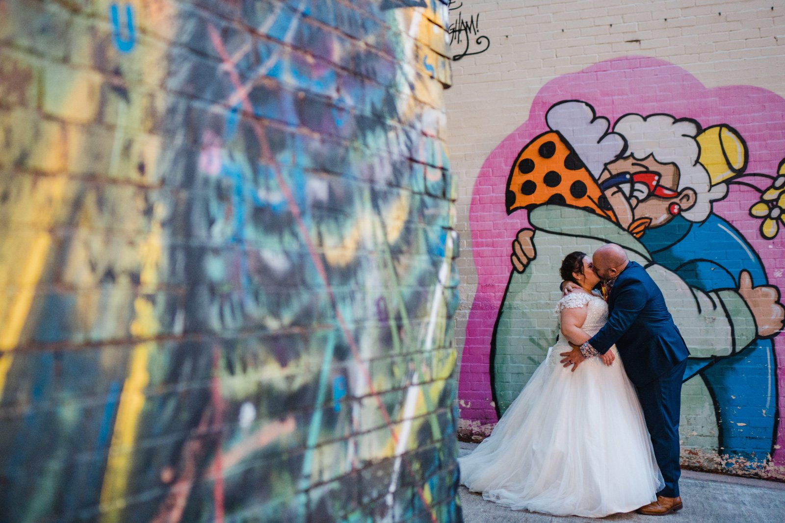 bride and groom kissing in front of graffiti in Digbeth - 2022 wedding round up no nonsense heartfelt wedding photography leeallenphotos