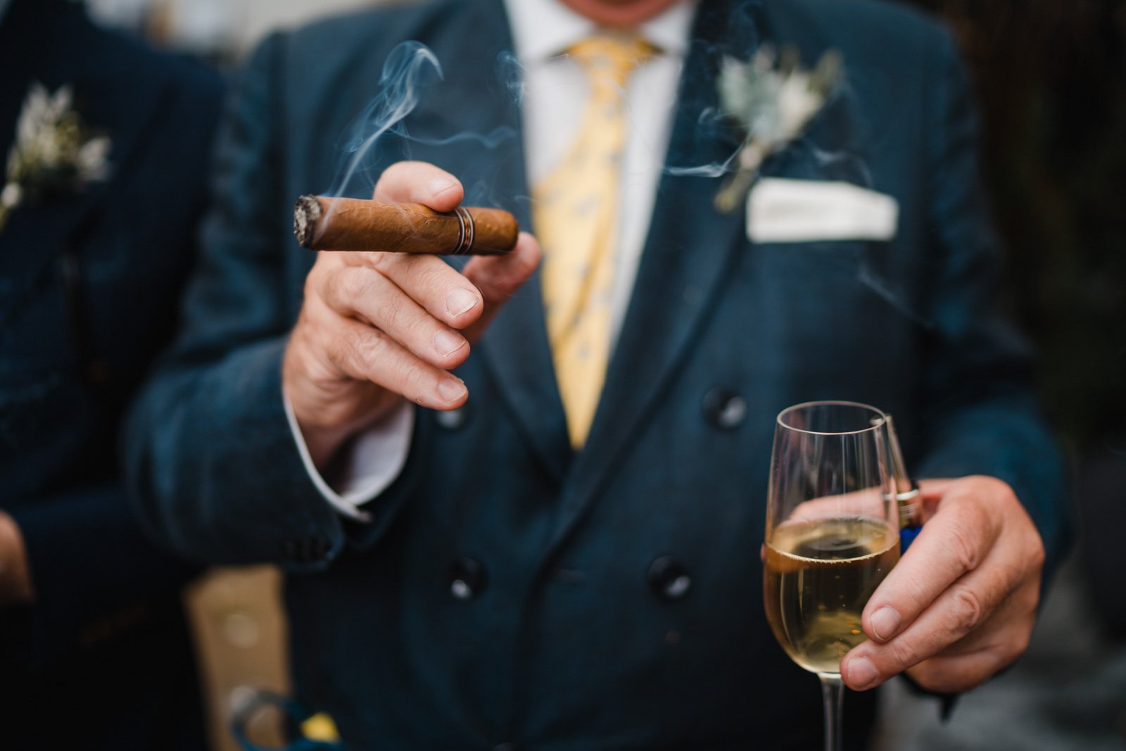a wedding guest with a cigar and a glass of champagne - 2022 wedding round up no nonsense heartfelt wedding photography leeallenphotos