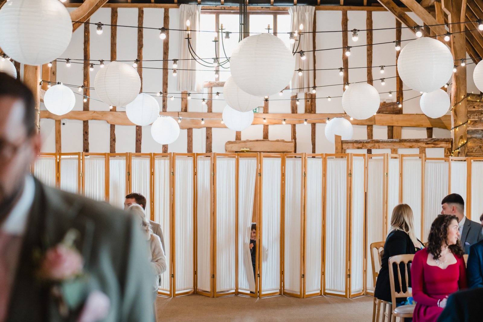  a small child peeks out of from a curtain before the wedding ceremony - 2022 wedding round up no nonsense heartfelt wedding photography leeallenphotos 