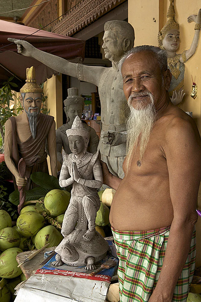 a sculptor poses with his creations in central phnom penh