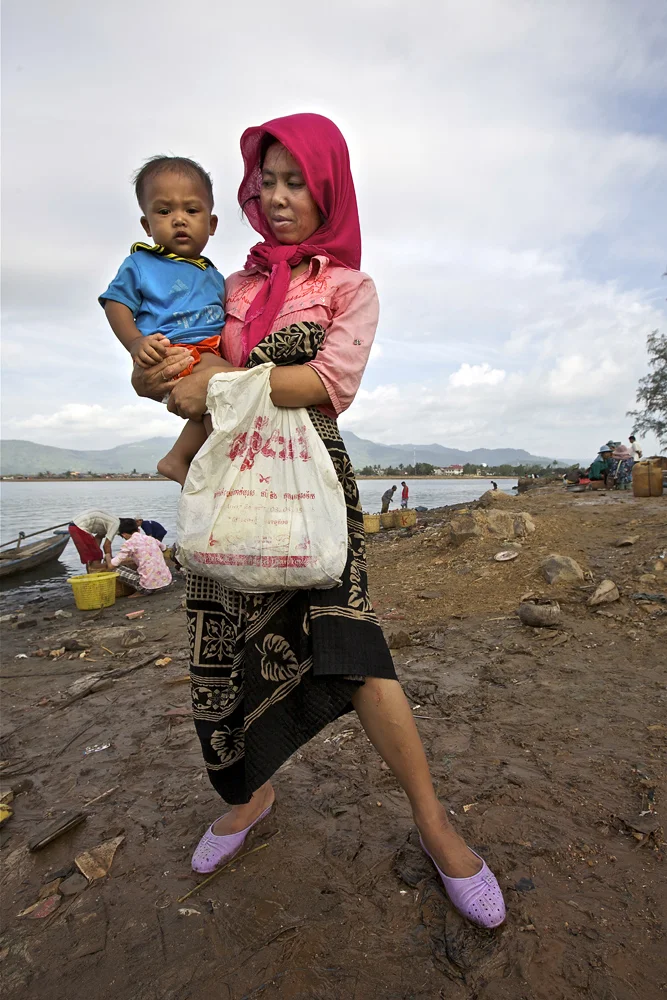 mother and child at the end of the morning fish market, kampot, southern cambodia