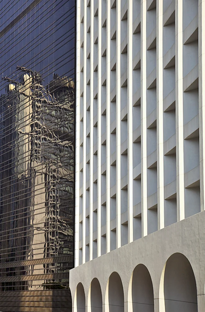 the clean white facade of the murrary building, one of hong kong's first skyscrapers and modernist landmark built in 1969, stands in contrast to the reflection of the hsbc building designed by norman foster and completed in 1985