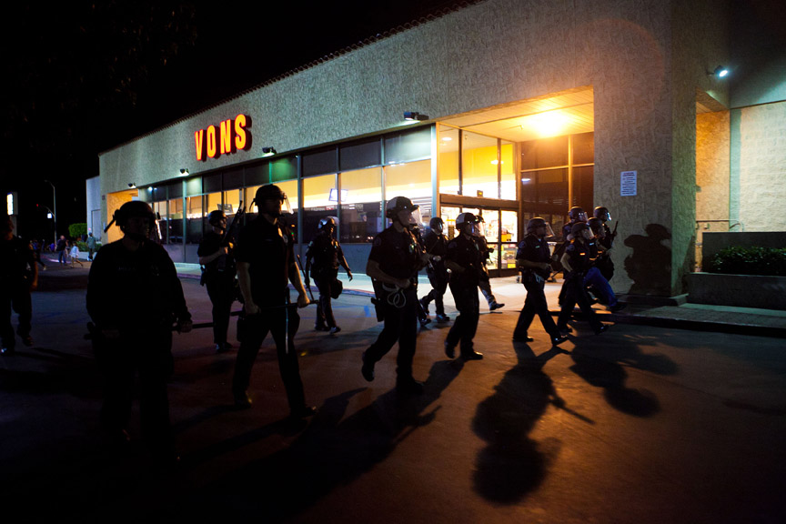  A scrimmage line of police officers march through an Anaheim shopping center.&nbsp;    