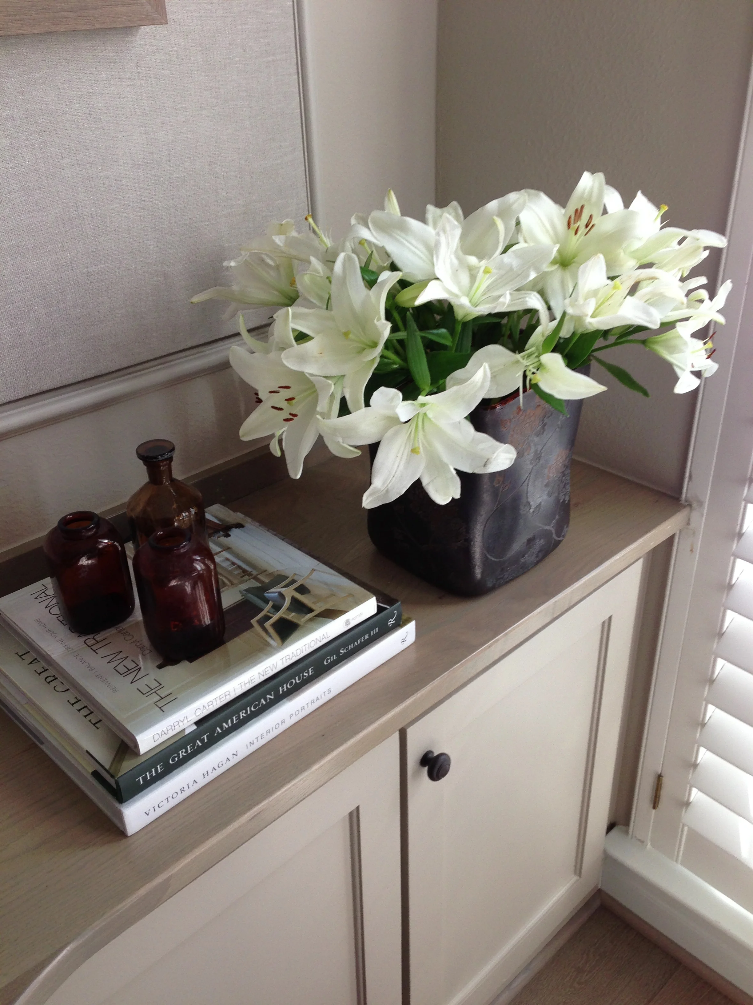 Stacked books with glass bottles | Bookshelf Styling Tips | Carla Aston, Designer