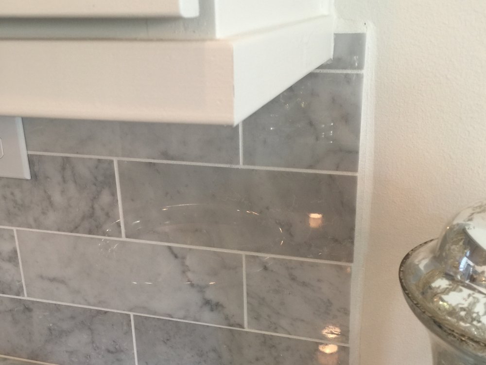 This kitchen tile backsplash does not align with the upper cabinet and appears to hand in mid-air with an unfinished look that has not been thoughtfully designed and detailed.