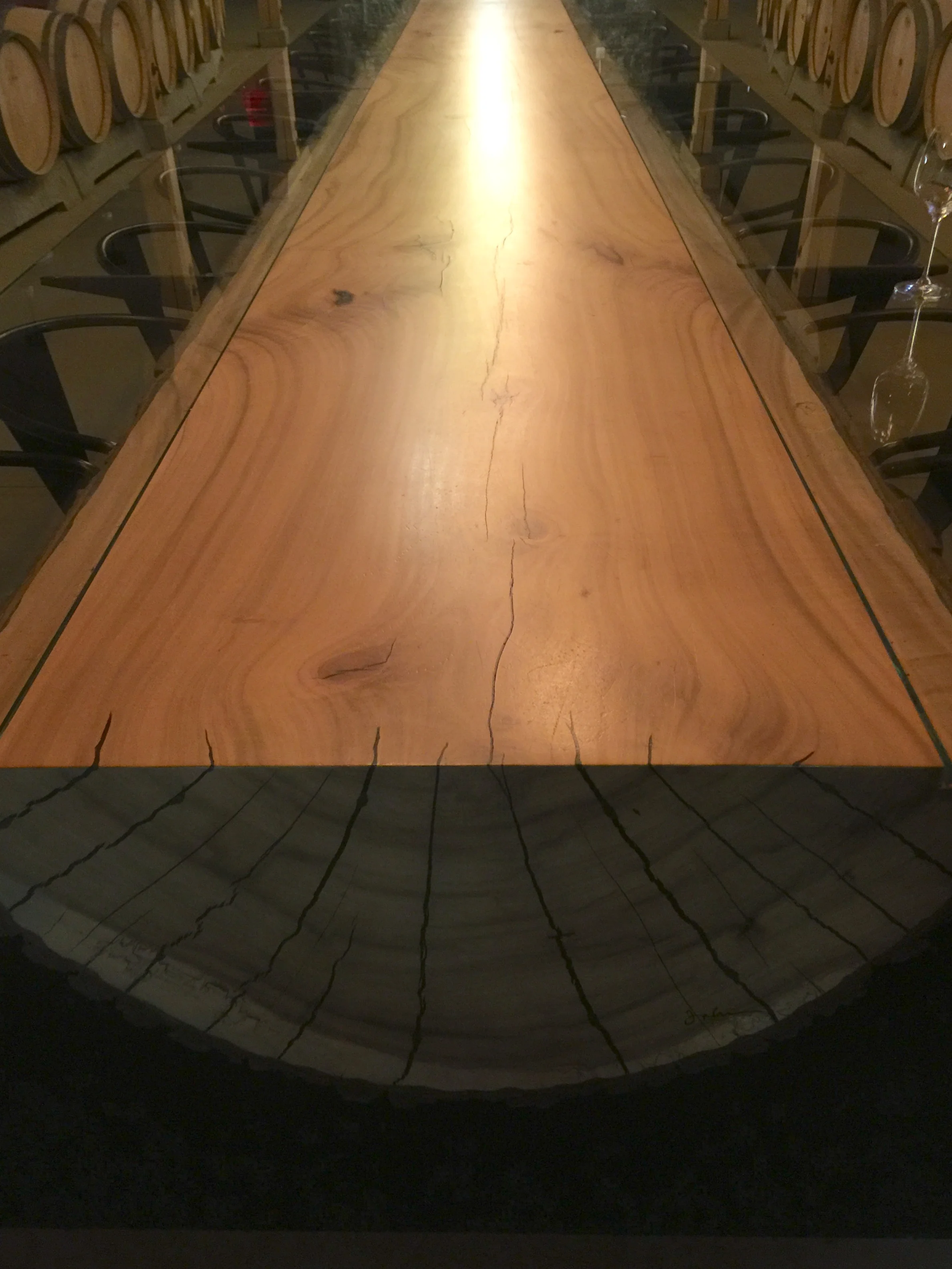 The tasting table made out of a half log with glass top extensions on the sides in the old stone building.
