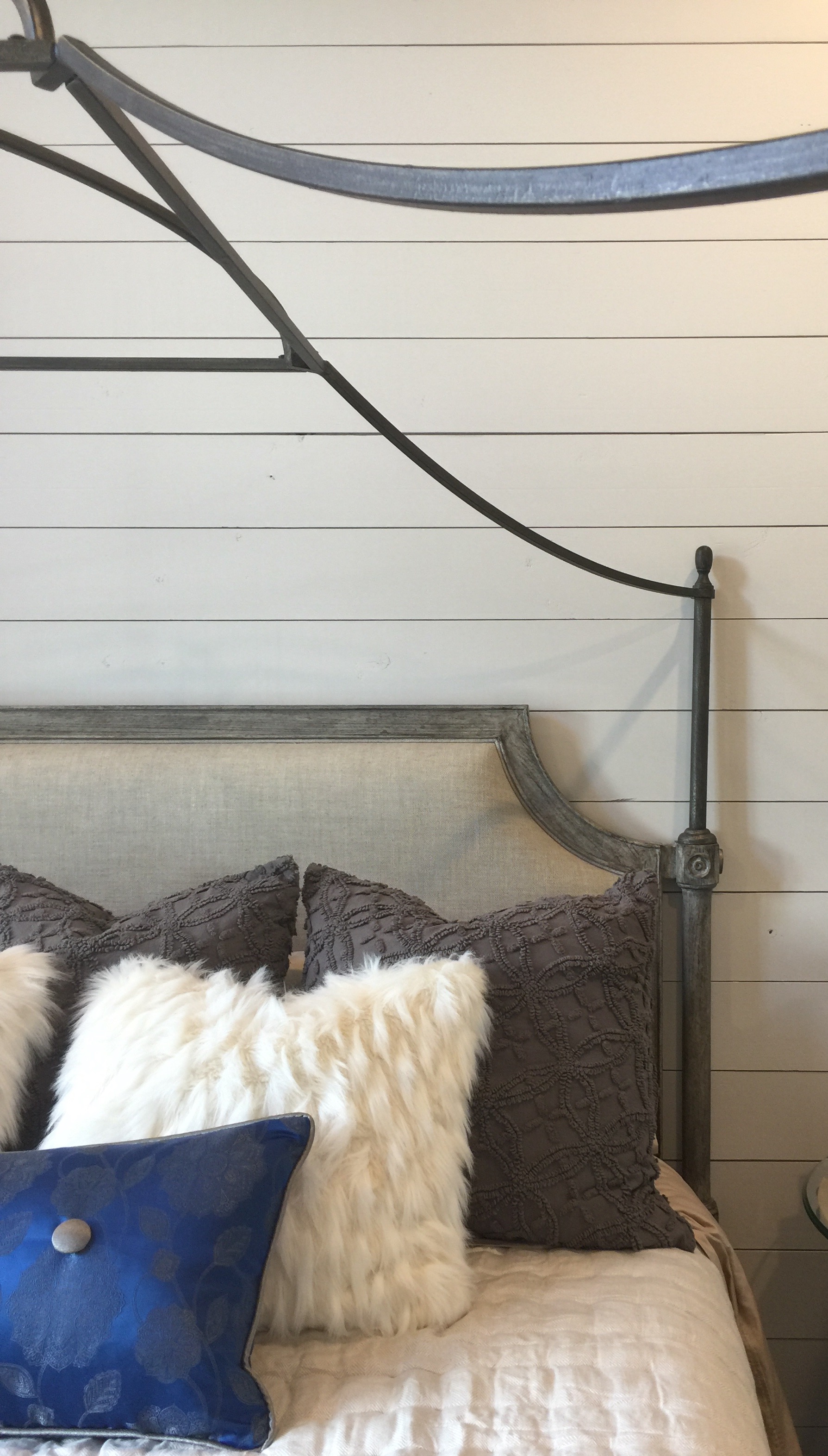 Shiplap wall with curvy iron bed in bedroom designed by Christina Mullen