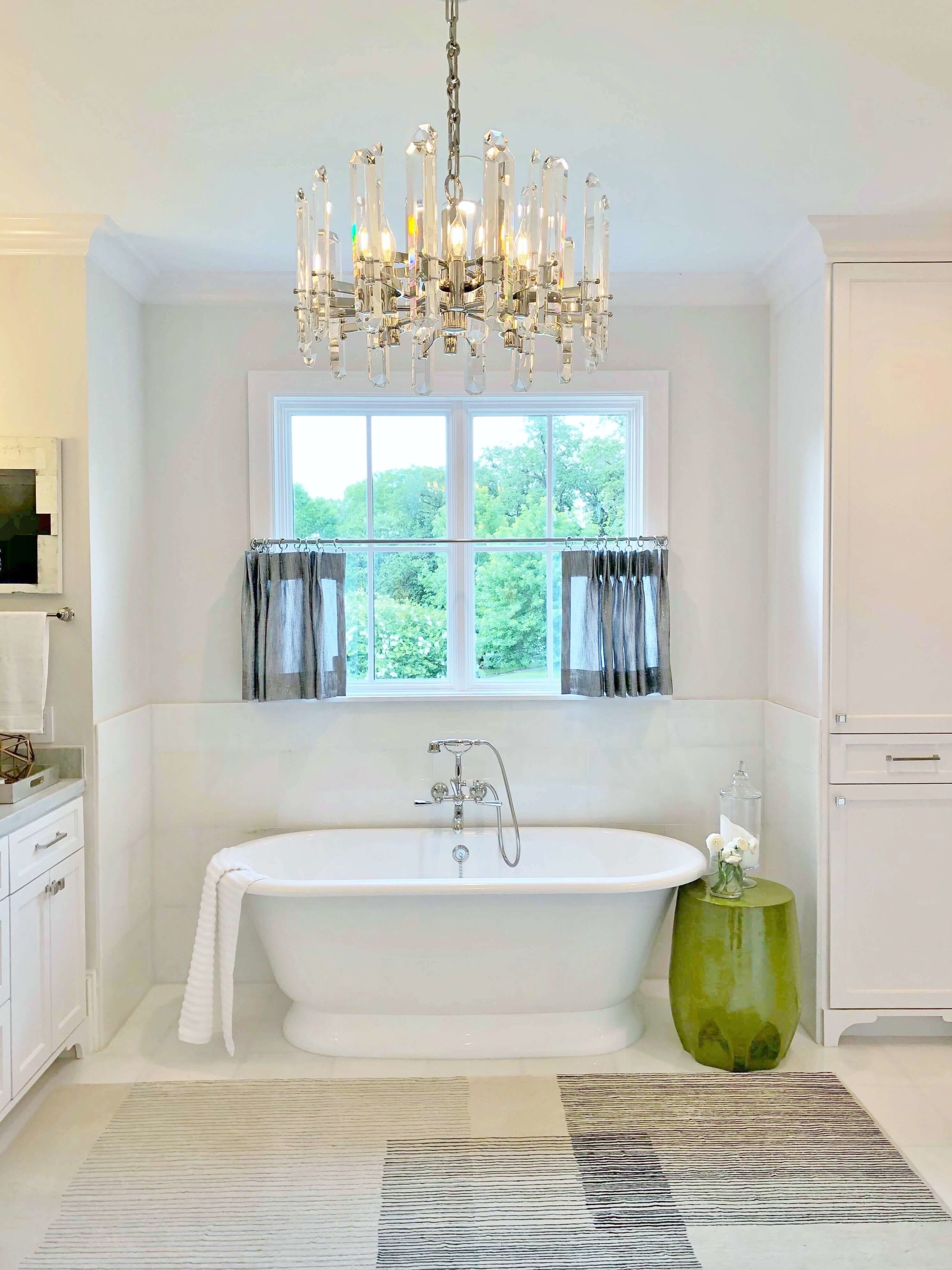 This beautiful master bath with a free-standing tub, pretty cafe curtain and glam light fixture, designed by Brooke Bowman of Bowman Design Studio, fits the luxurious feel of this home in River Oaks, Houston. ASID River Oaks Showhouse #masterbath #bathdesign #freestandingtub