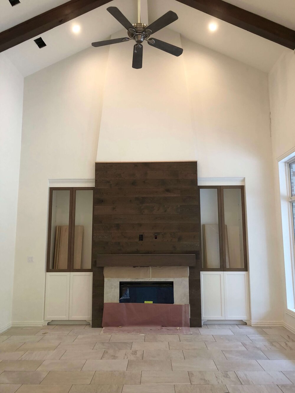 Construction pic - Wood flooring was used to clad this fireplace wall and provide a backdrop for the large tv. A quartzite slab surrounds the firebox. Designer: Carla Aston