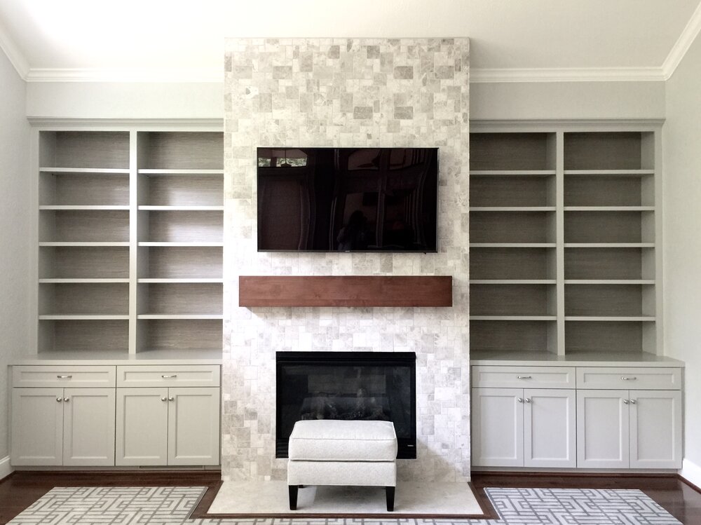 Fireplace wall with natural stone tile cladding fireplace, tv mounted above mantel. Grasscloth installed in backs of bookshelves. Carla Aston, Designer