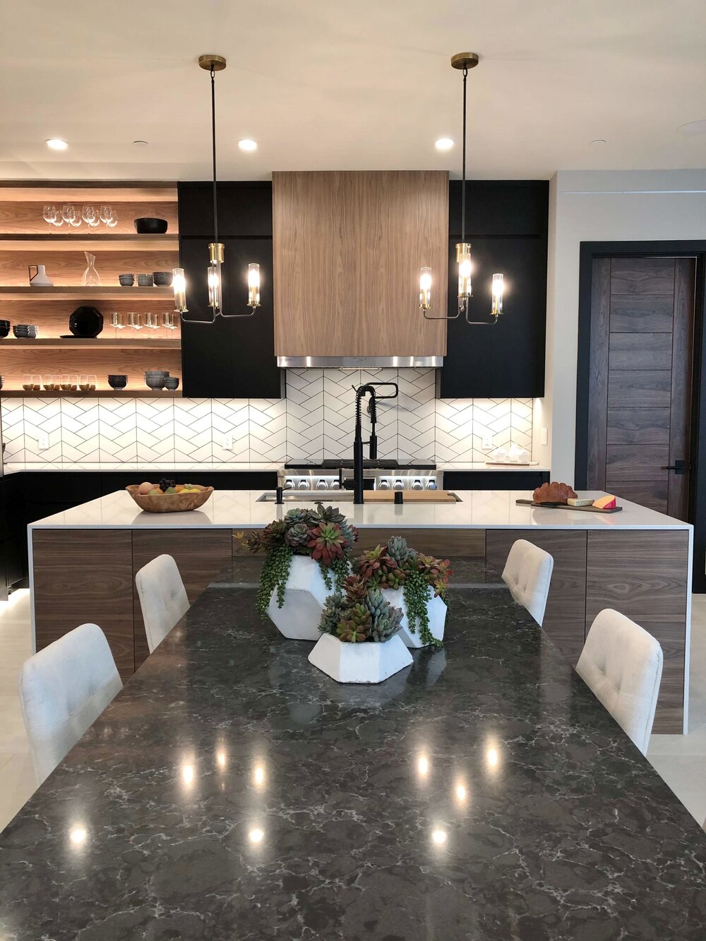 The built - in waterfall table attached to the island reaches out to the big dining table beyond. The New American Remodel TNAR | #remodeling #remodel #kitchenideas #kitchendesign