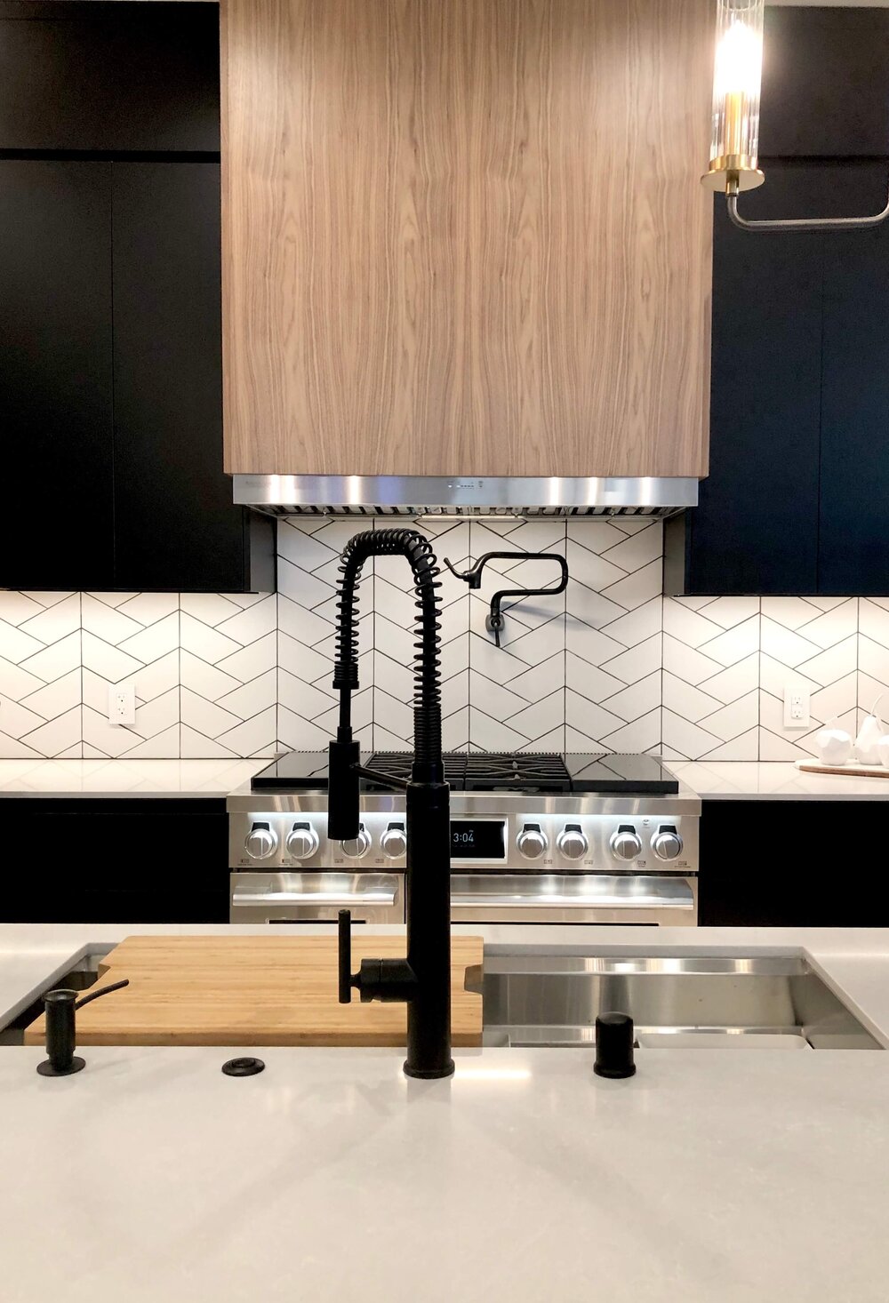 The SKS Appliances range with sous vide cooking takes center stage under the contemporary wood venthood in this contemporary kitchen in The New American Remodel TNAR | #remodeling #remodel #kitchenideas #kitchendesign