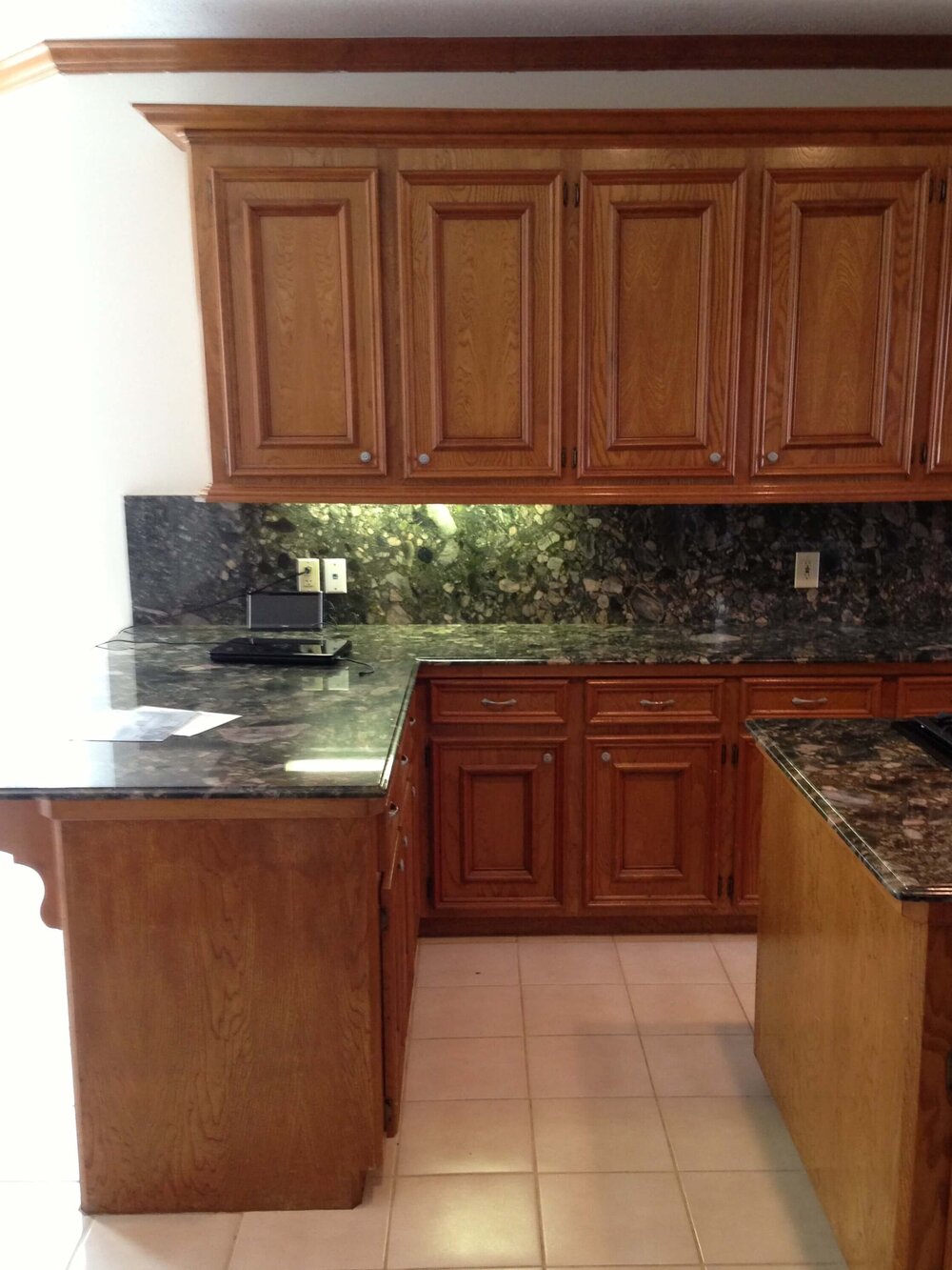 BEFORE REMODEL - Kitchen cabinets were dated and had heavy mouldings. They were short of the 9’-0” high ceiling.