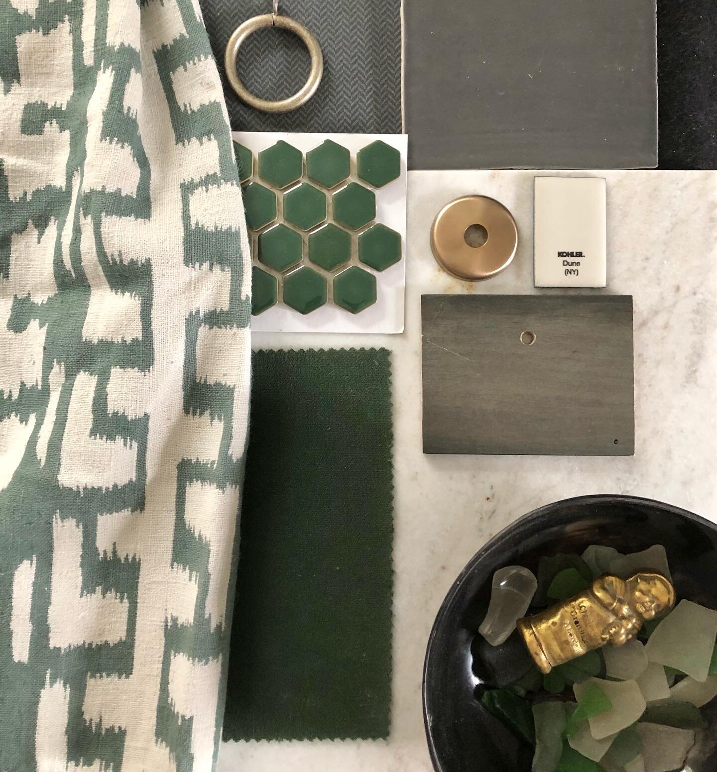 A masculine vibe in this primary bathroom with charcoal gray tweedy look wallpaper, gray watercolor look tile, white marble counters, charcoal gray cabinetry and hunter green mosaics for the shower floor and niches. A graphic linen drapery and @crypt