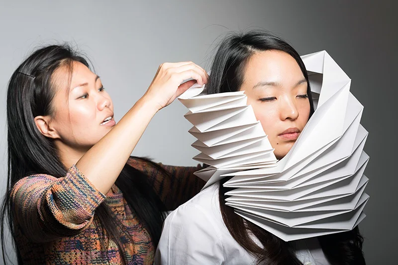 Christine fits the folded paper to model Eunsung Yoon. Photo by Don Toye.